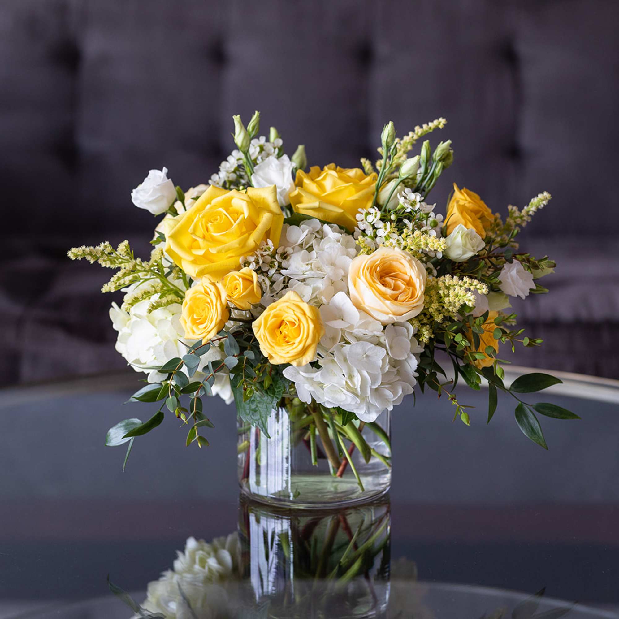 Yellow and white rose bouquet in a clear glass vase