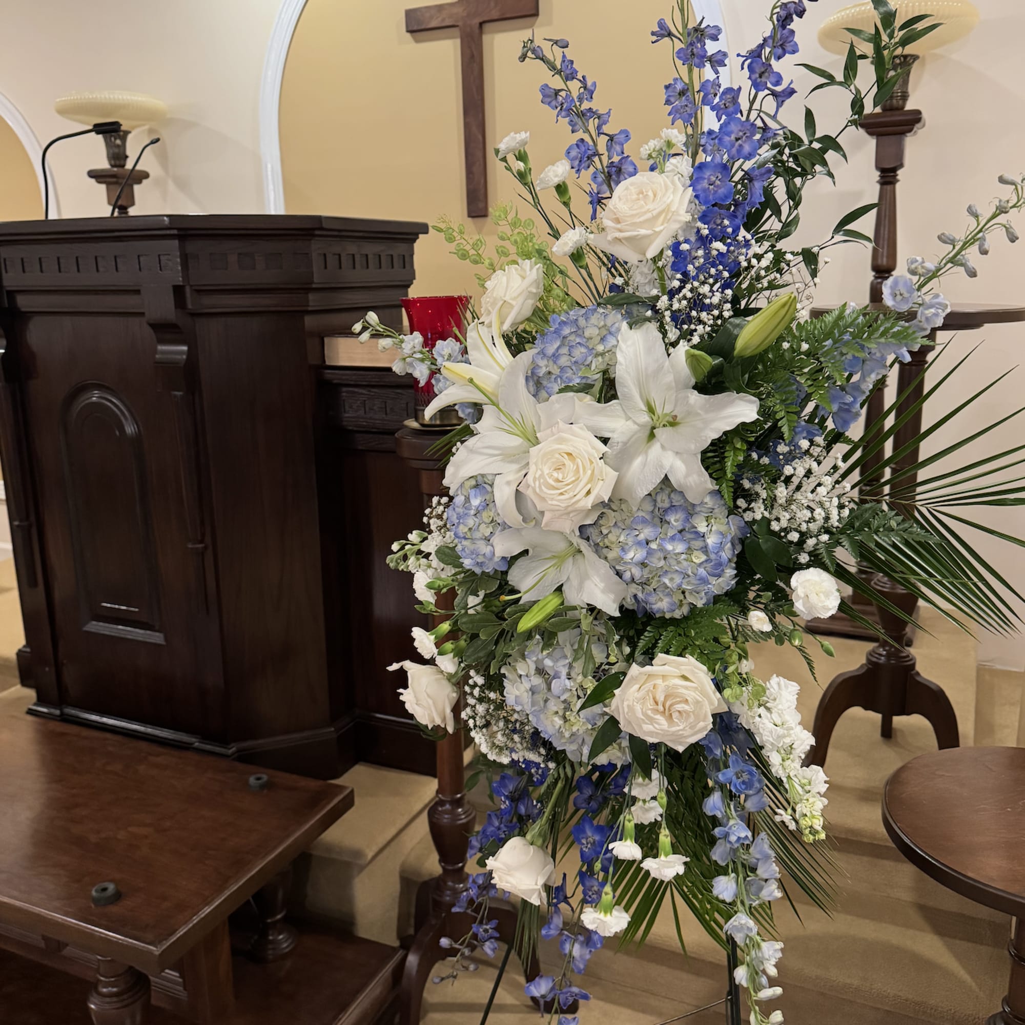 Tall white and blue floral spray on a stand in a church