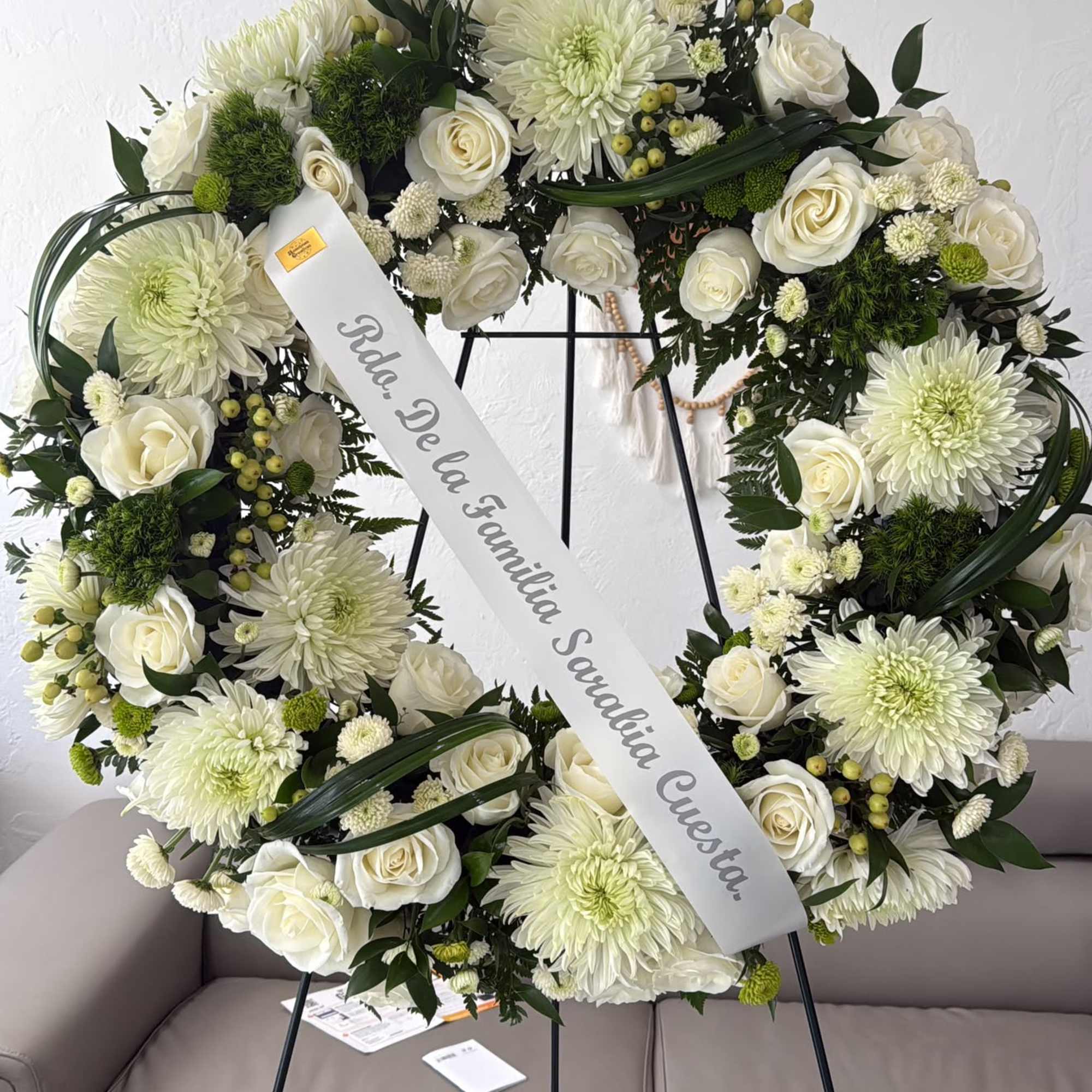 White floral wreath on a stand with a condolence ribbon