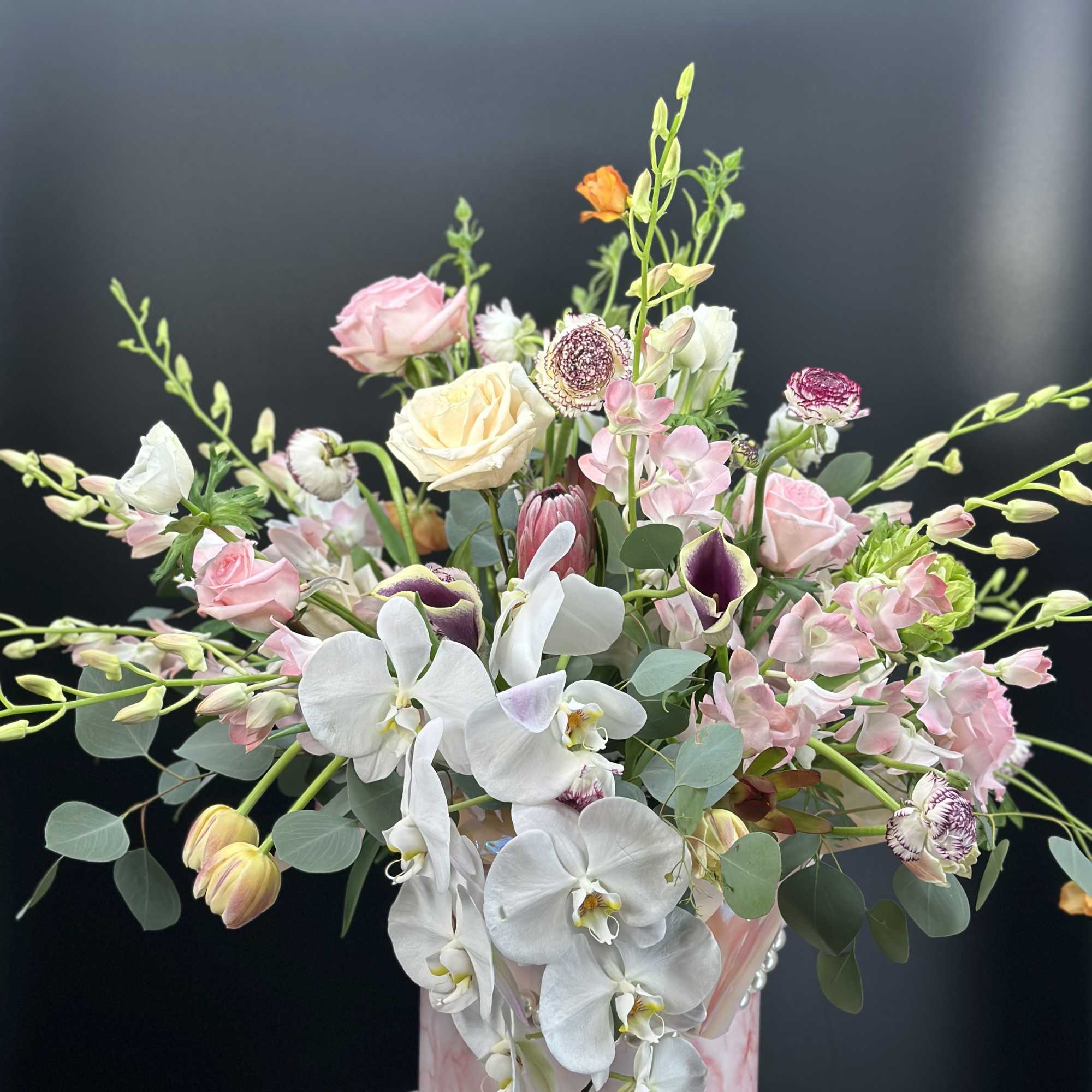 Mixed bouquet with white orchids and pink roses in a pink round box