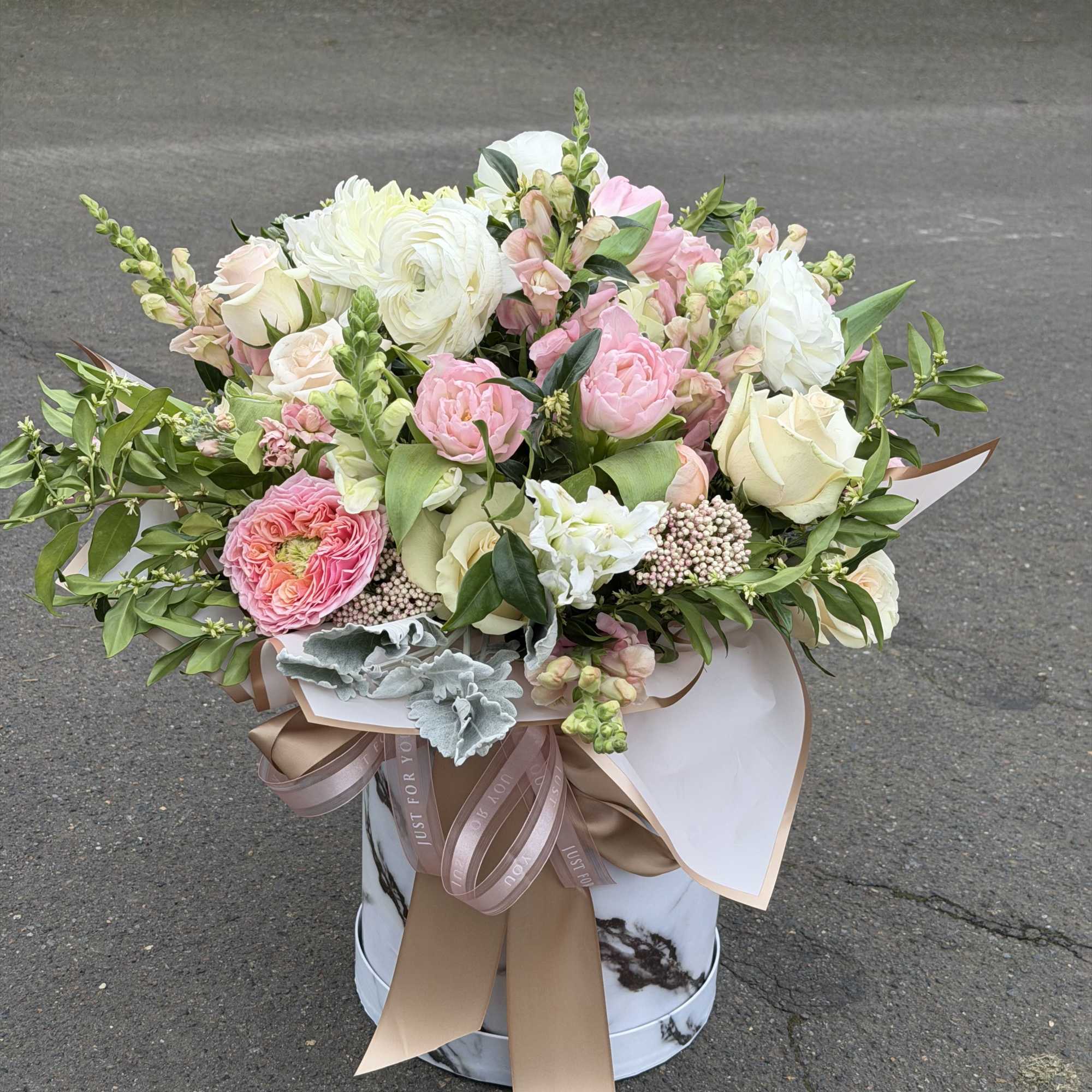 Pink and white bouquet in a marble-patterned hat box with ribbon
