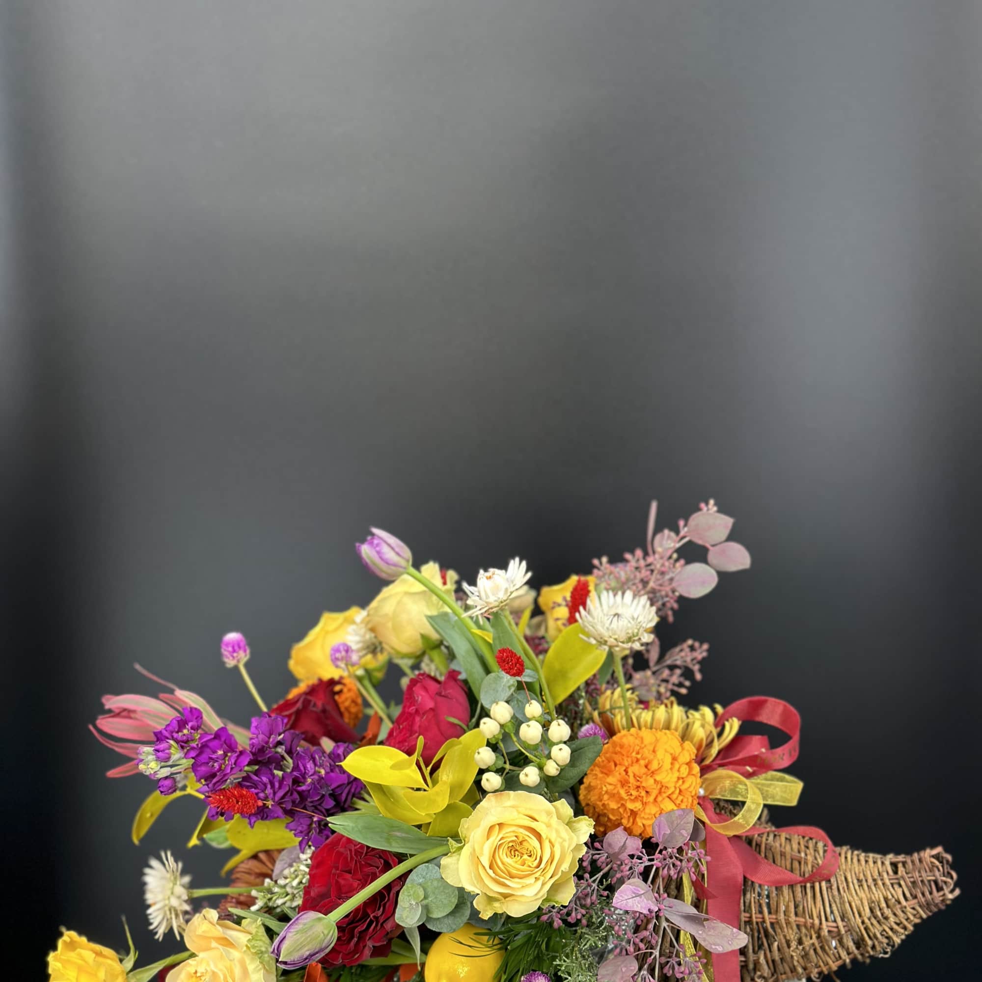 Colorful mixed bouquet with roses and marigolds in a woven basket