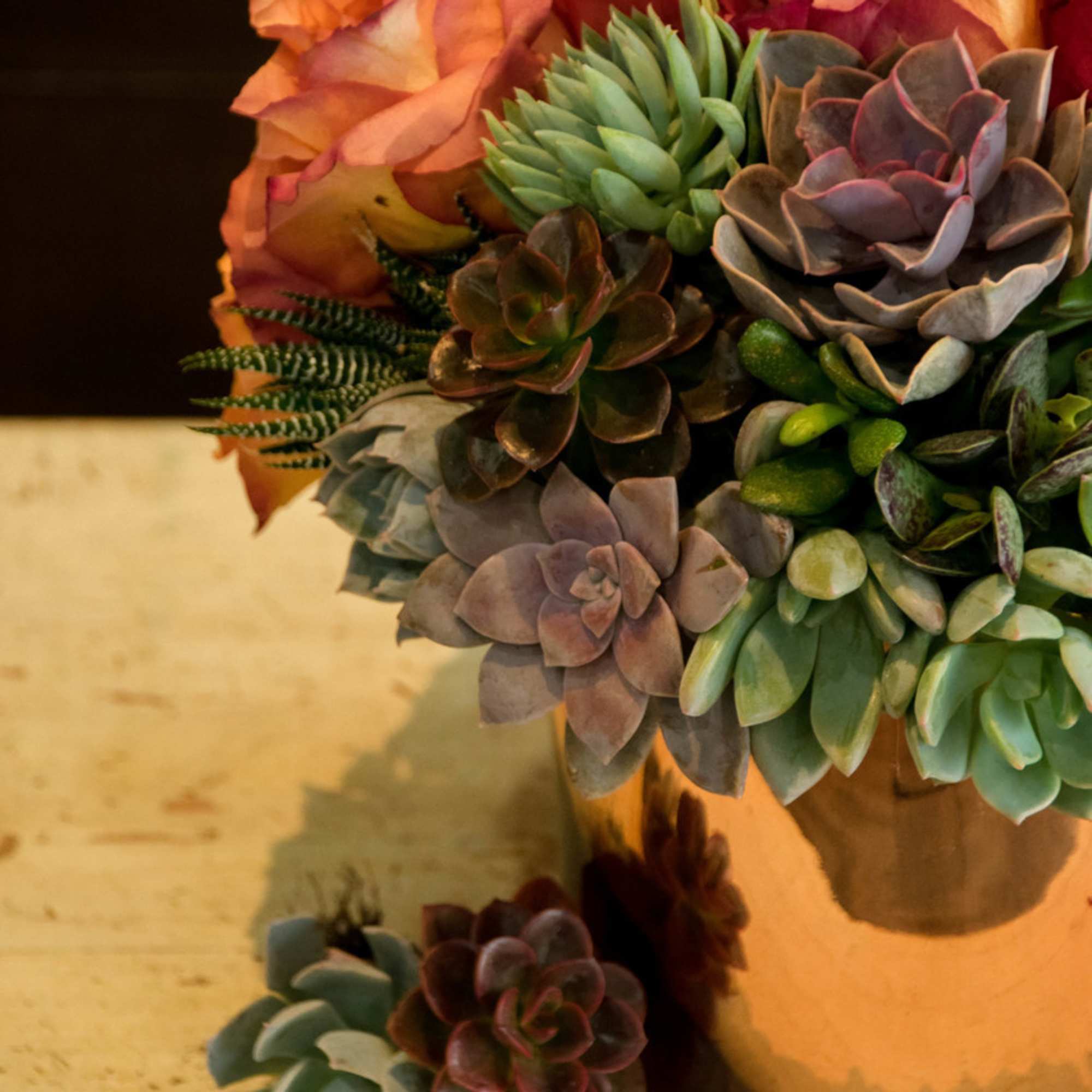Succulent bouquet with peach roses in a vase