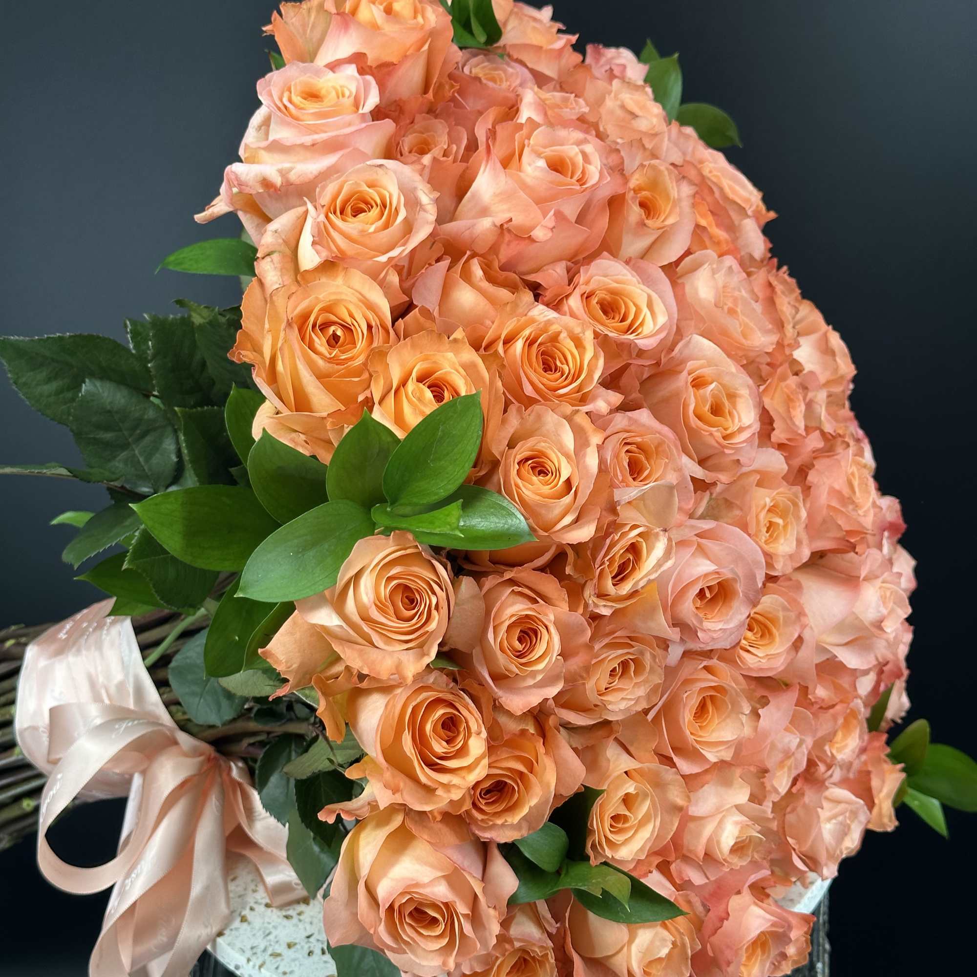 Peach rose bouquet with a satin ribbon in a decorative container
