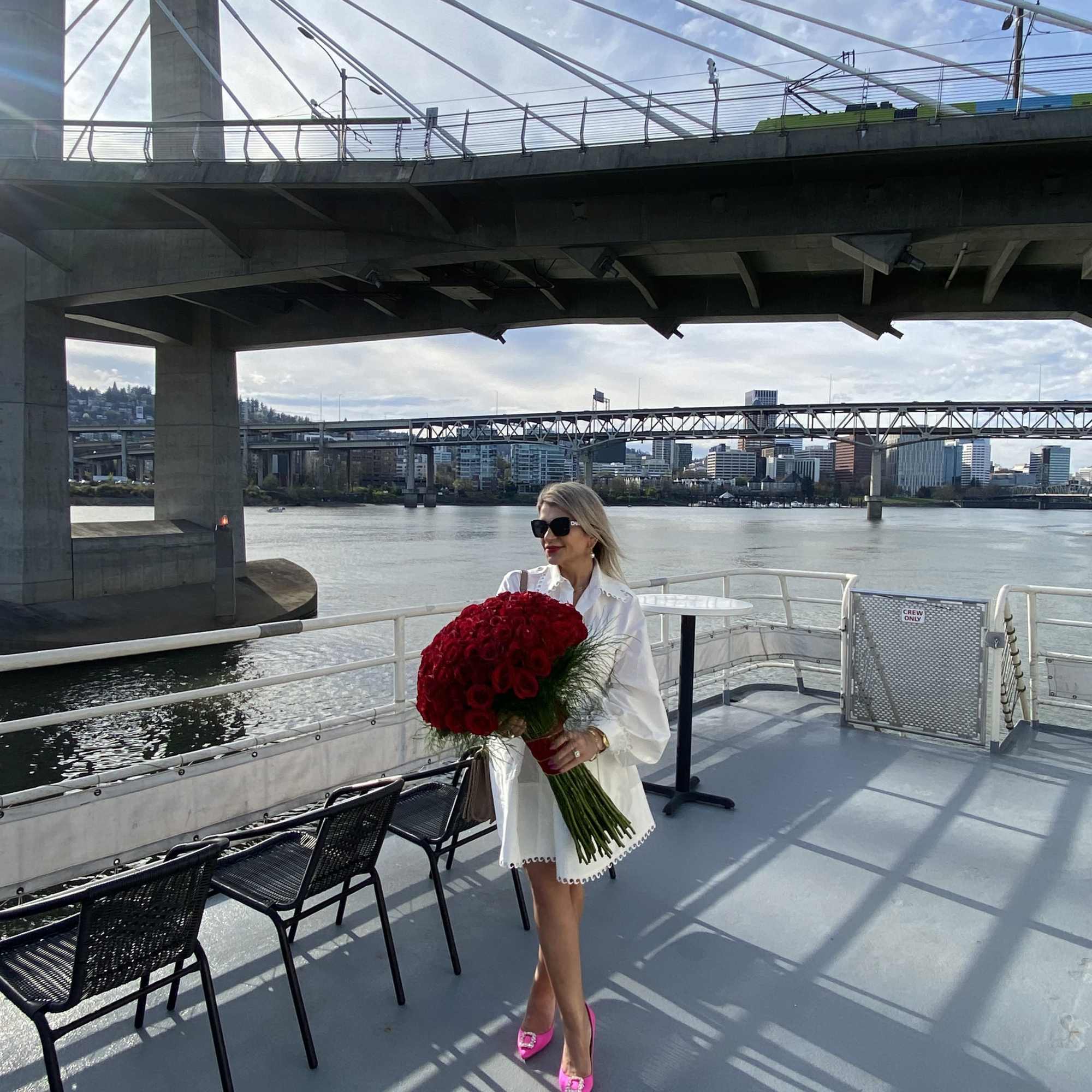 Woman holding a large bouquet of red flowers on a boat deck