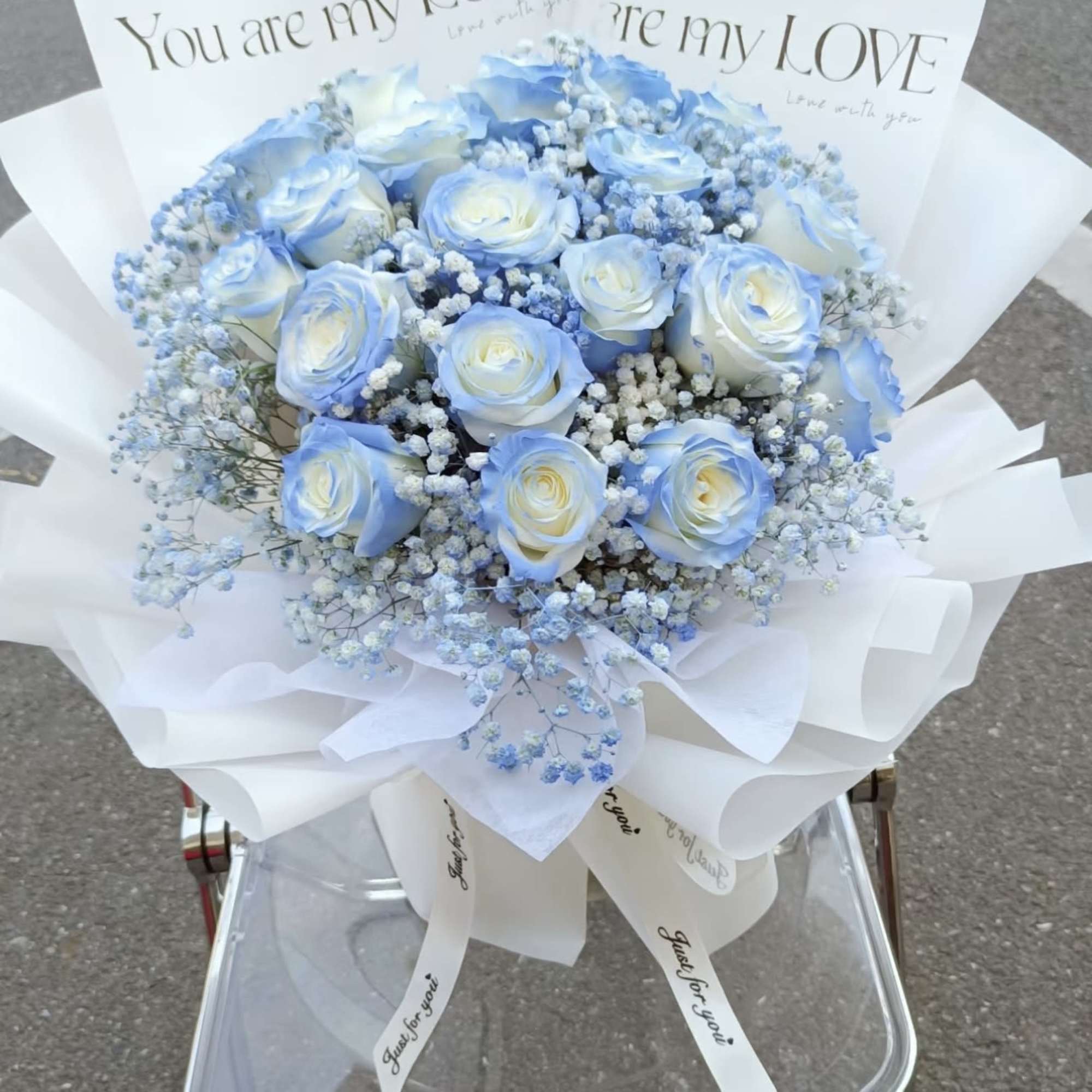 Blue and white rose bouquet with baby's breath in white wrap