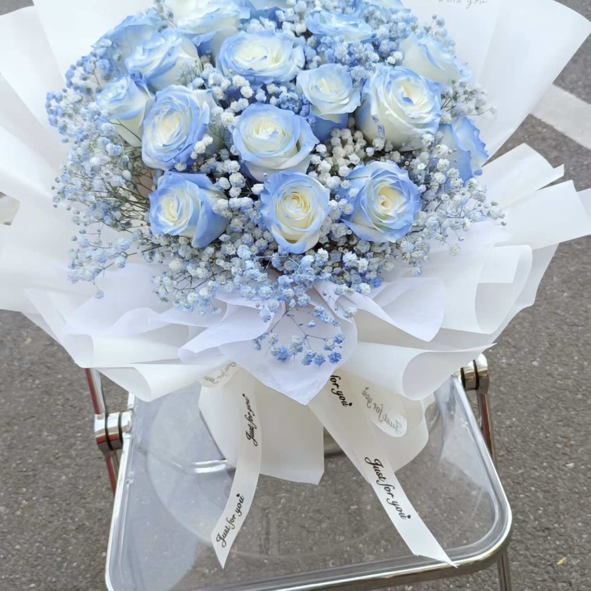 Bouquet of pale blue and white roses wrapped in white paper