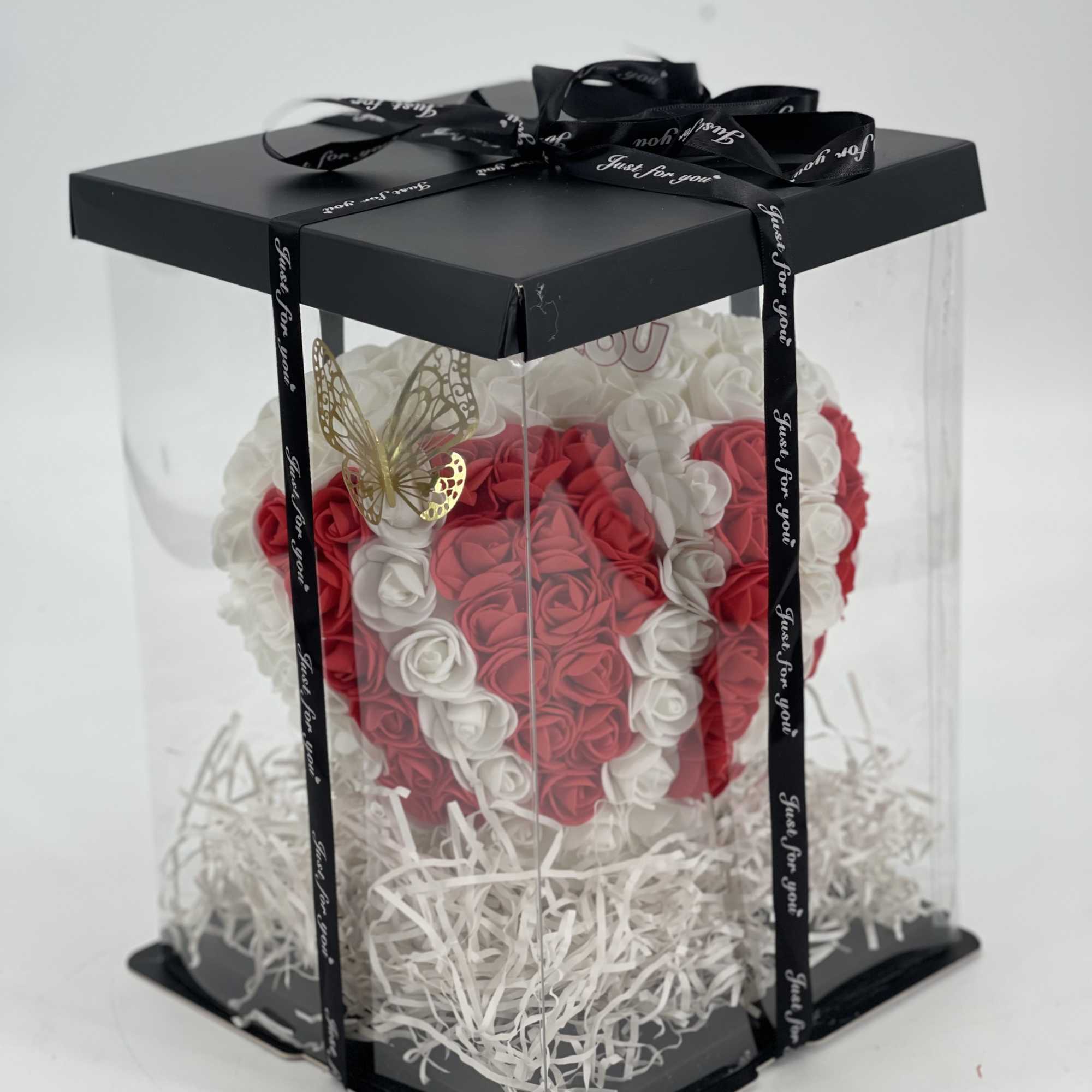 Heart-shaped rose arrangement in a clear gift box with a black ribbon