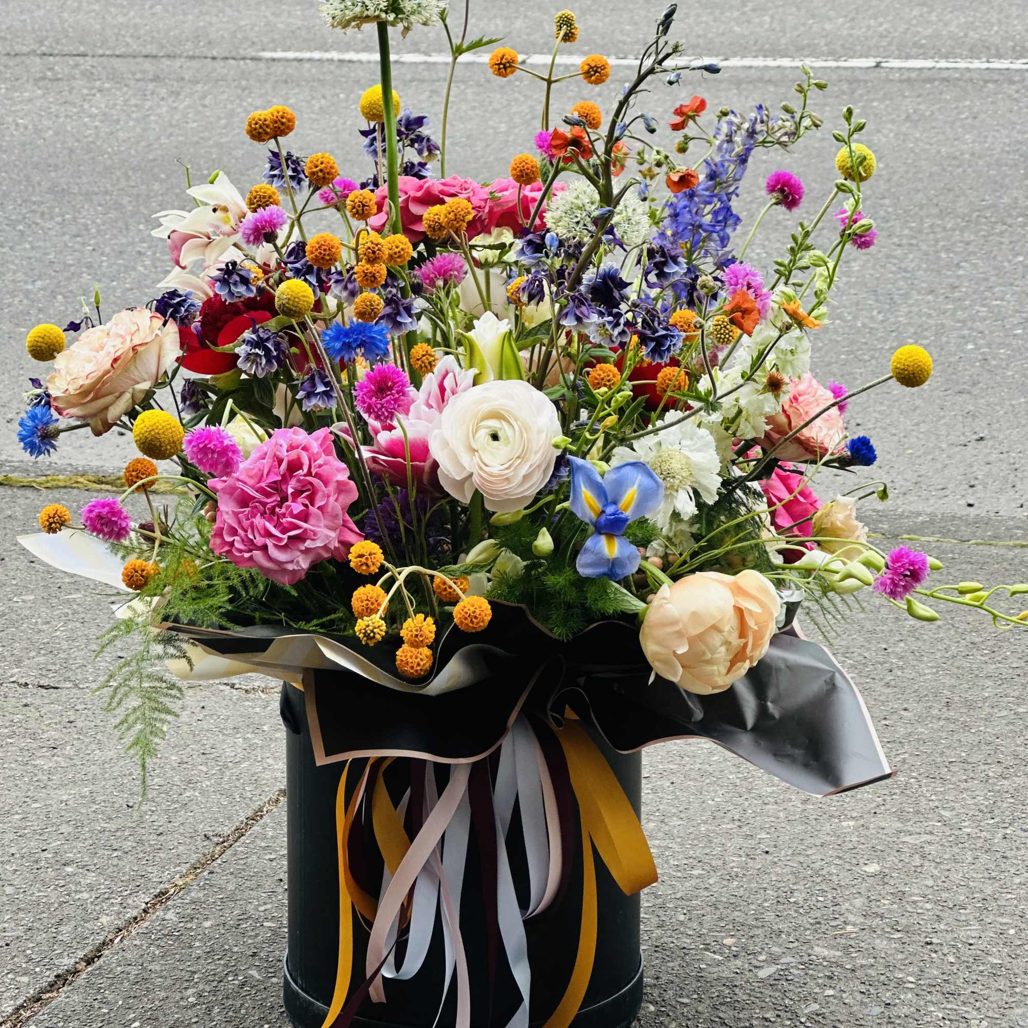 Colorful mixed bouquet in a black container with ribbon streamers