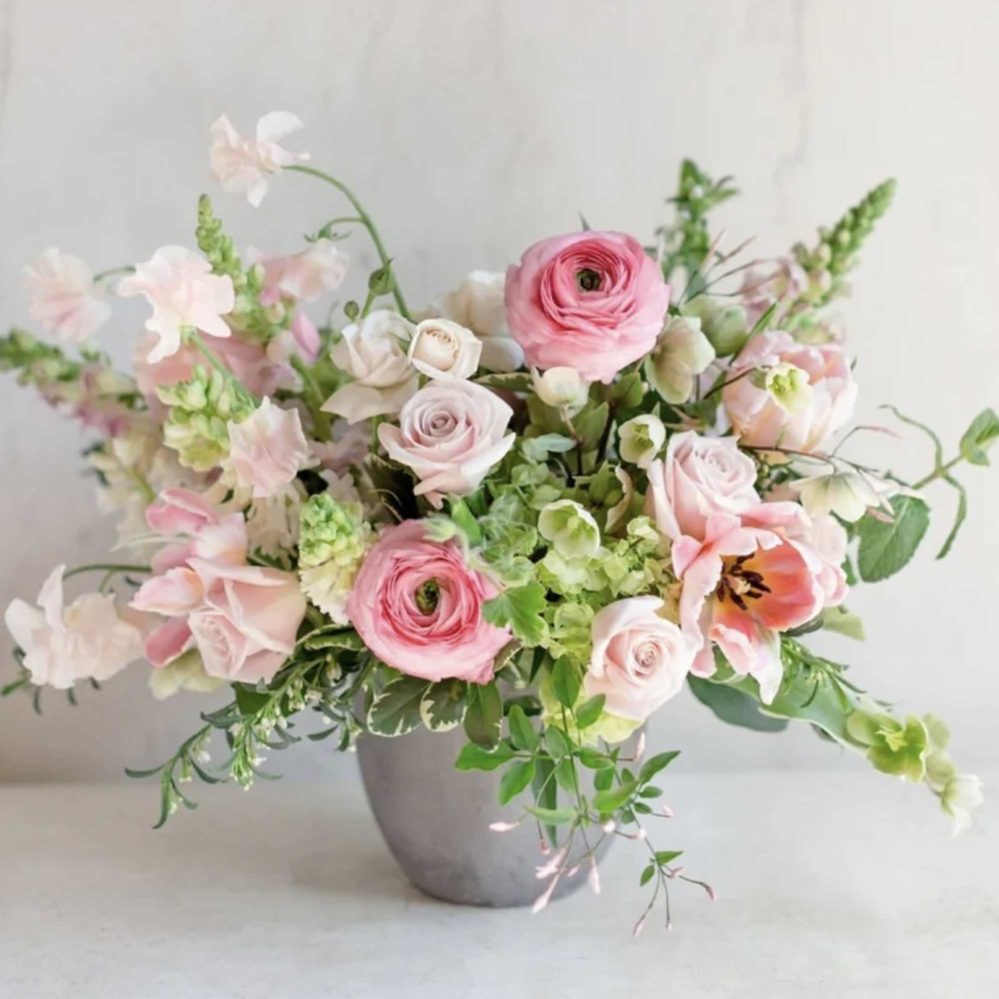 Pink and white mixed flower arrangement in a gray vase