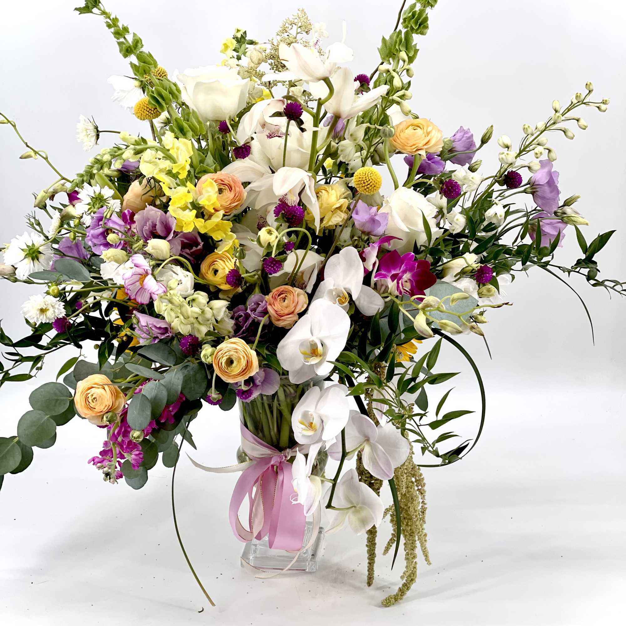 Large mixed bouquet in a clear vase with white orchids and pastel flowers