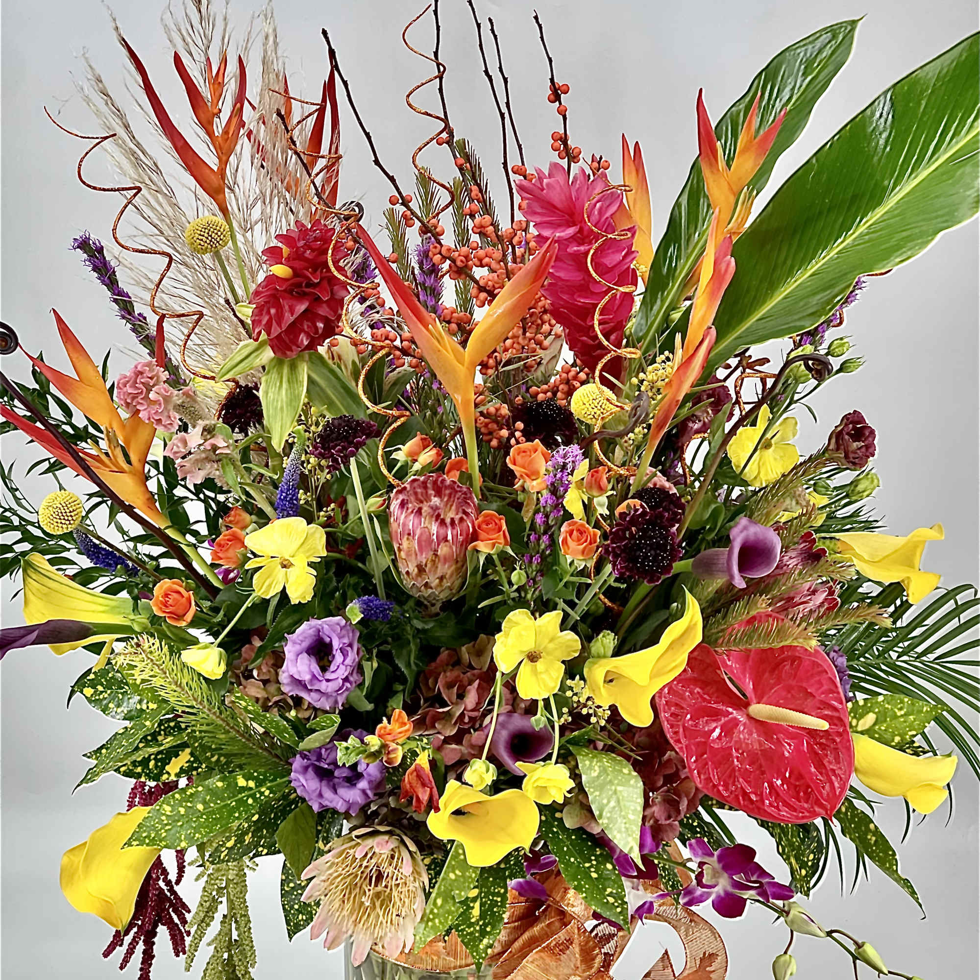 Large tropical bouquet in a clear glass vase with bright mixed flowers