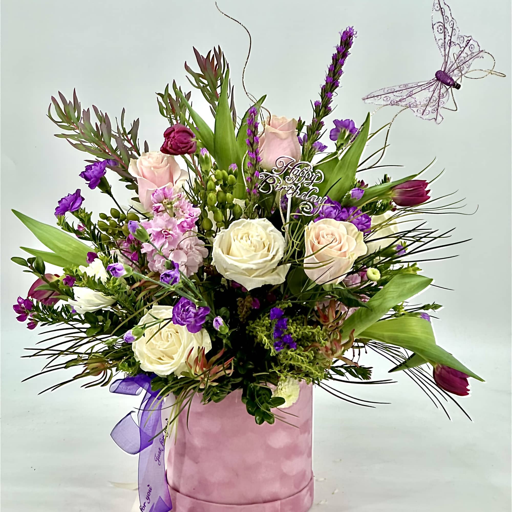 Pink and white rose arrangement in a pink hatbox with a purple butterfly pick