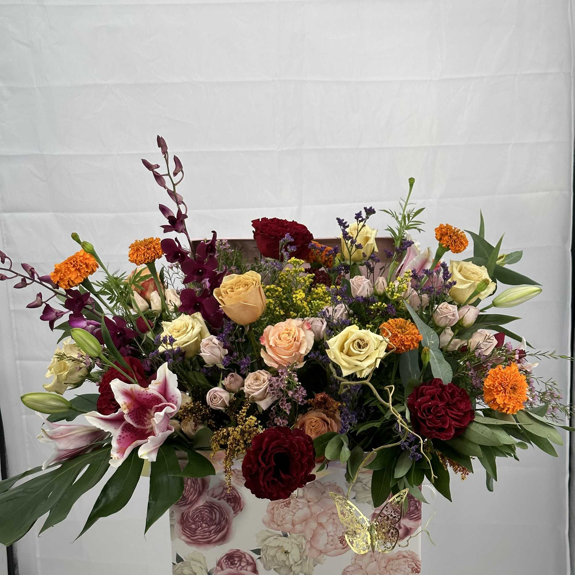 Large mixed floral arrangement in a decorative box on a stand