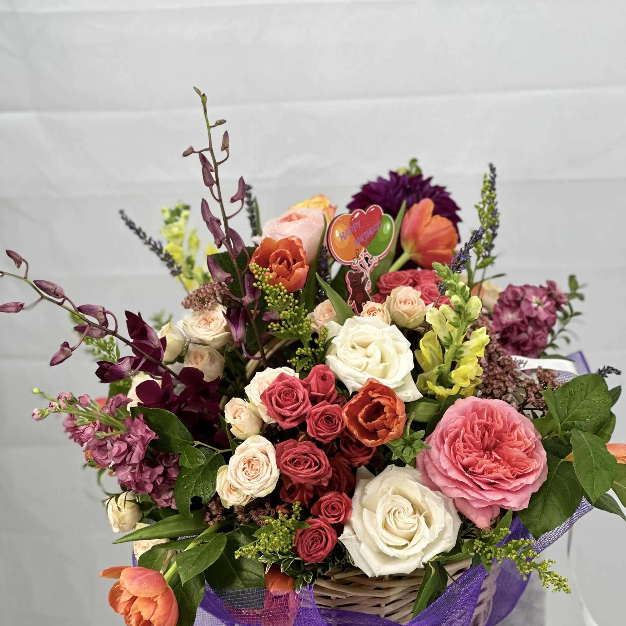 Mixed bouquet in a wicker basket with roses and tulips