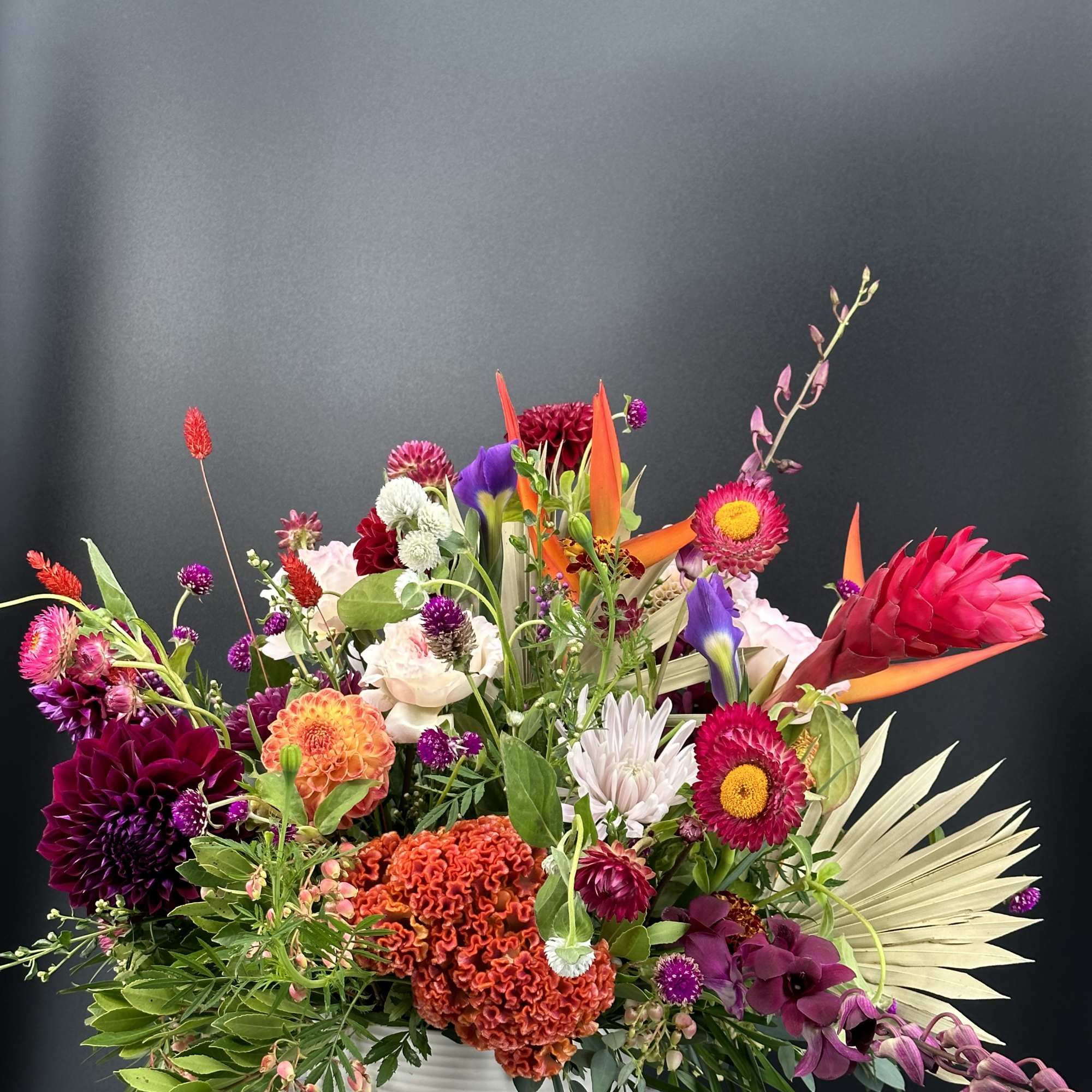 Colorful mixed flower arrangement in a white container