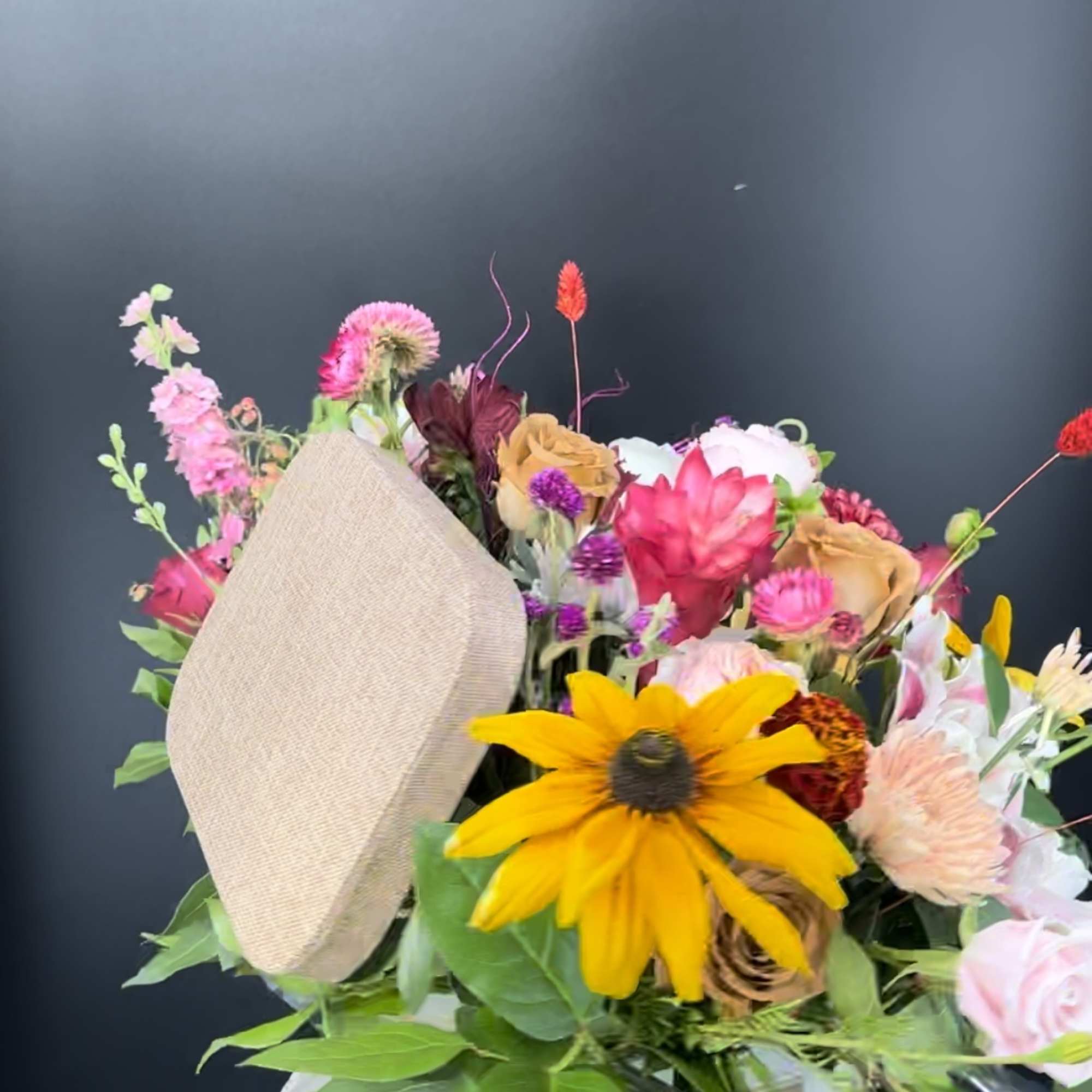 Mixed bouquet with a large yellow daisy and pink, peach, and white blooms