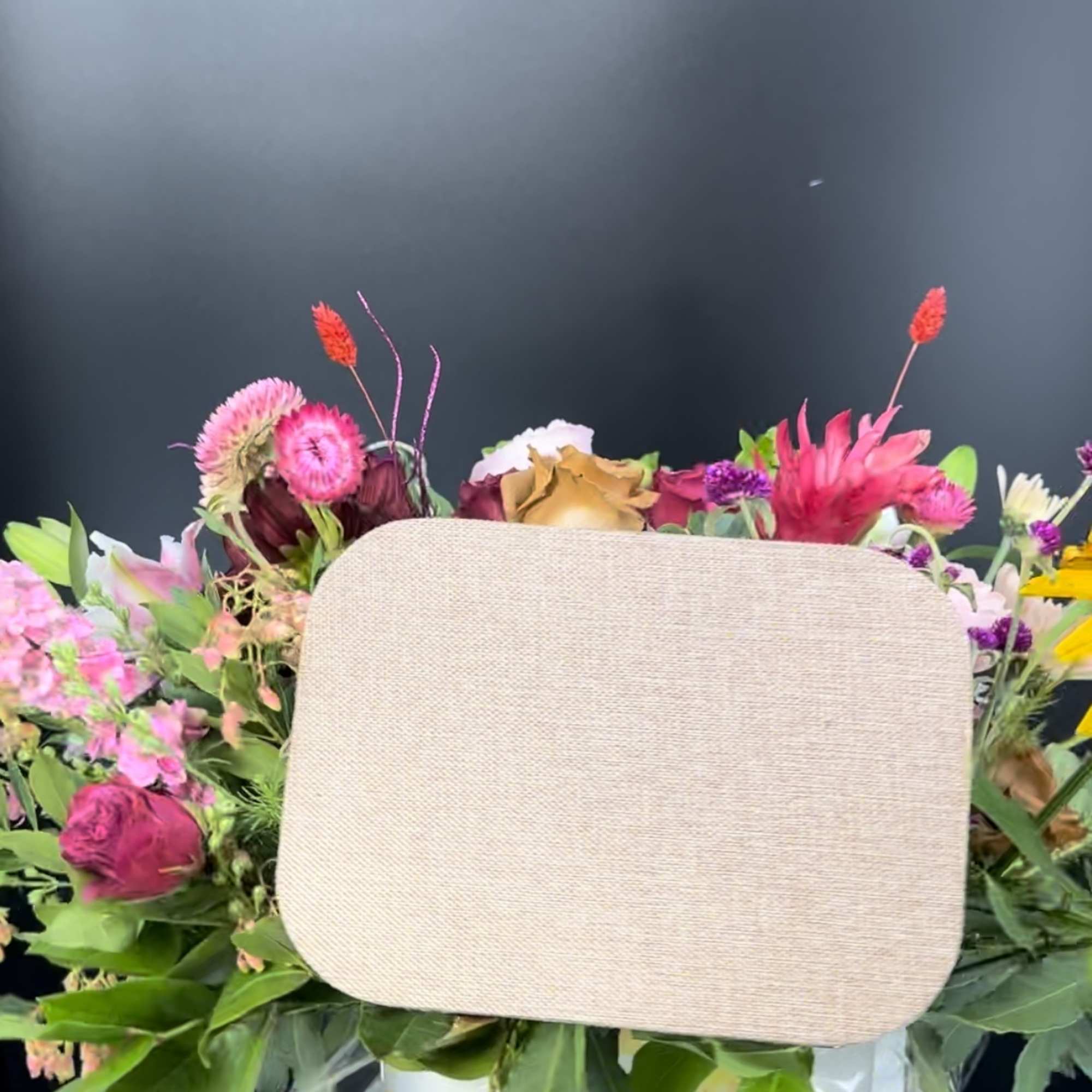 Mixed bouquet with pink and red flowers in a sunflower-print container