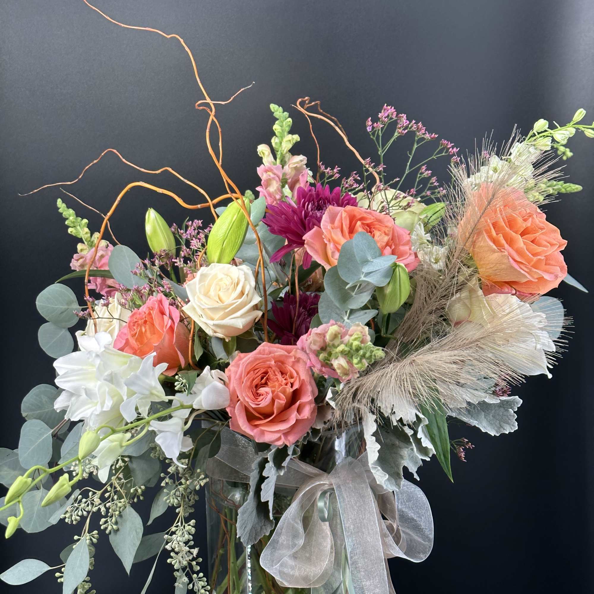 Mixed bouquet of roses, lilies, and chrysanthemums in a glass vase