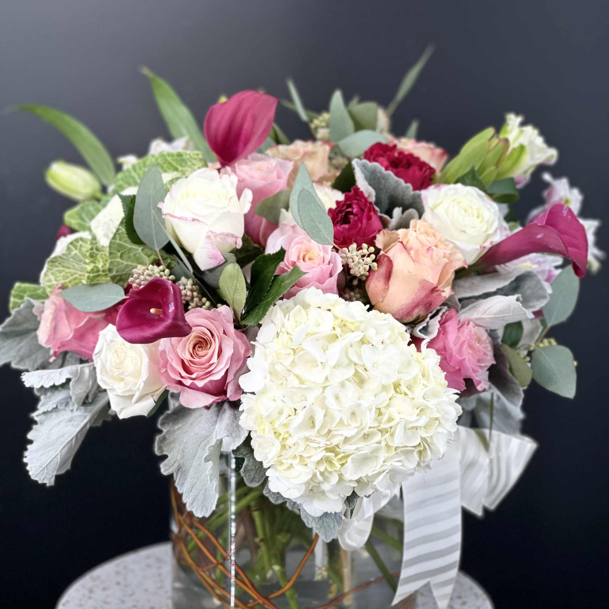 Pink and white floral arrangement in a glass vase with ribbon