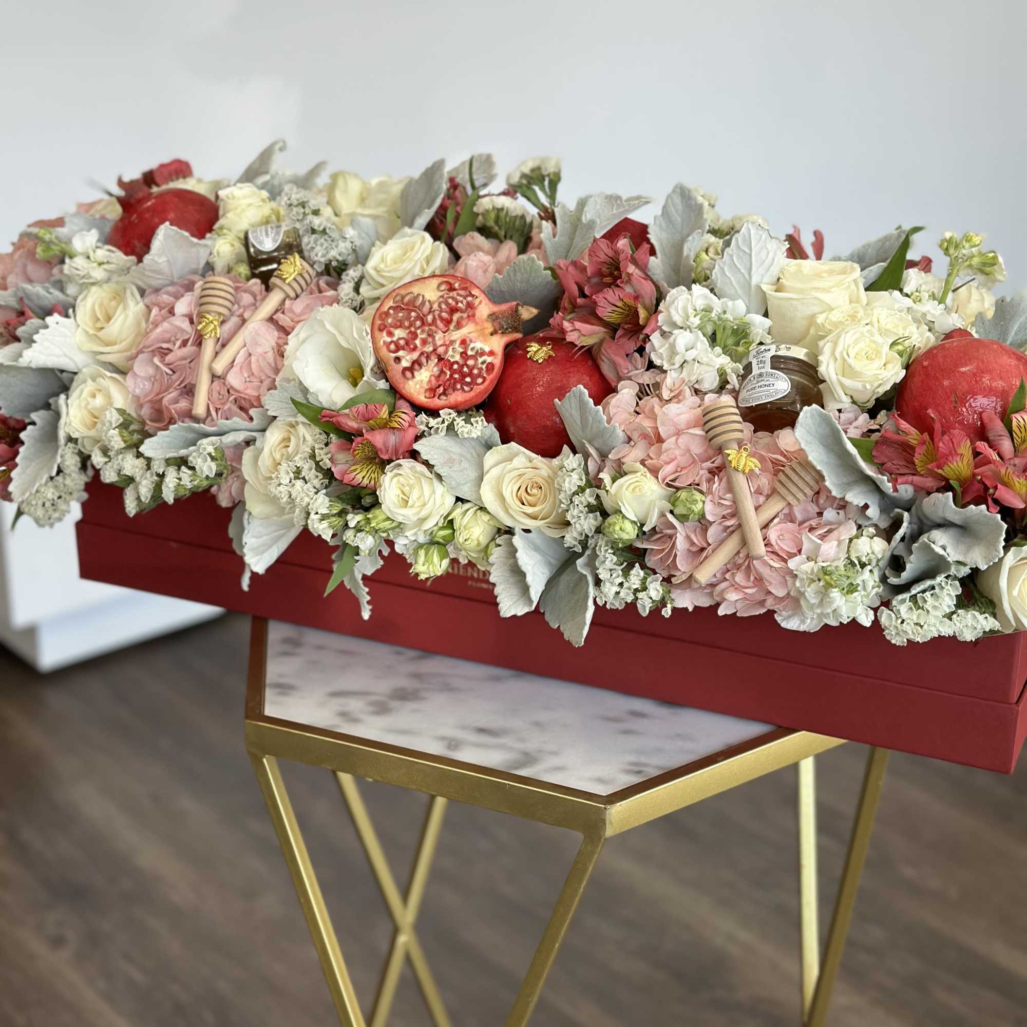 Long floral arrangement in a red box with roses, hydrangeas, and pomegranates