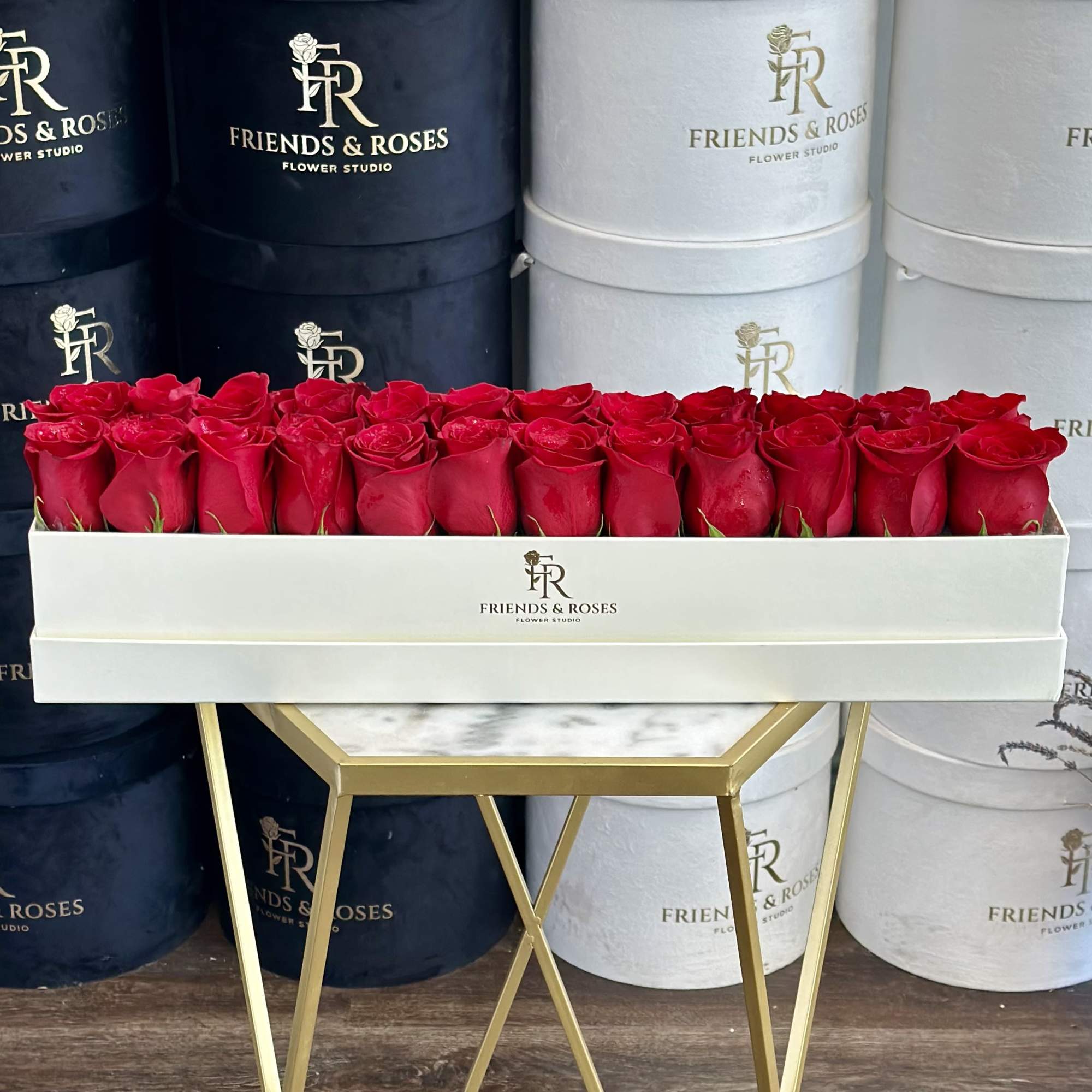 Long white box filled with red roses on a gold stand