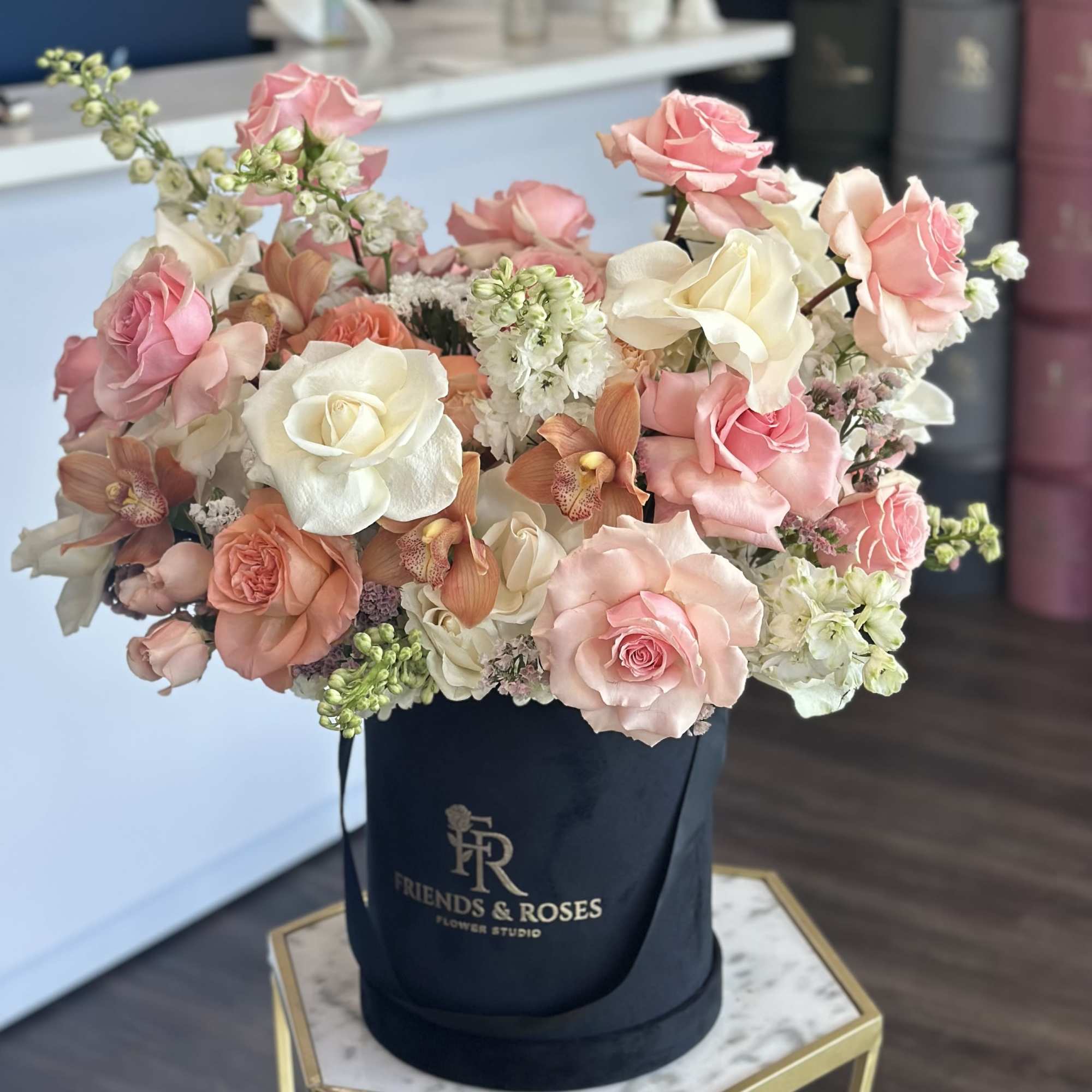 Pink and white roses arranged in a black hatbox