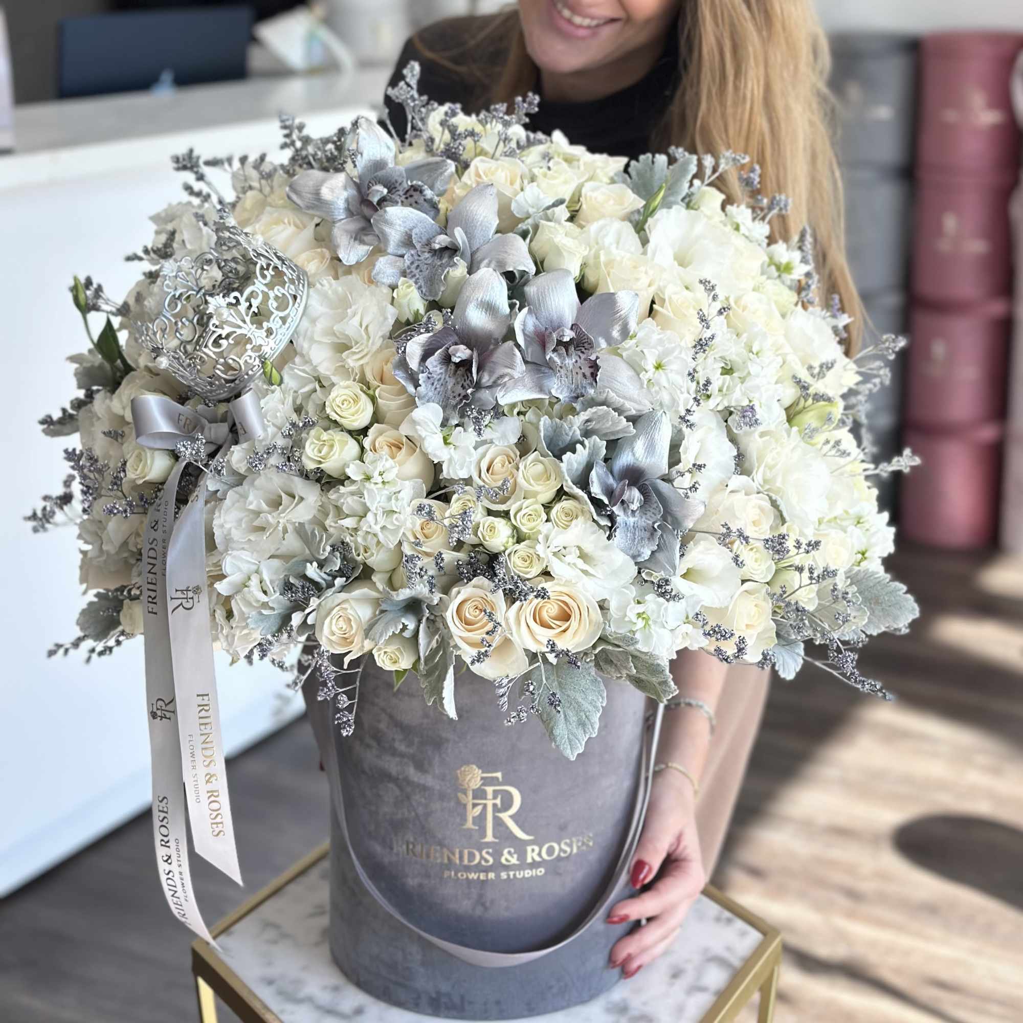 Large bouquet of white and pale cream flowers in a gray hatbox
