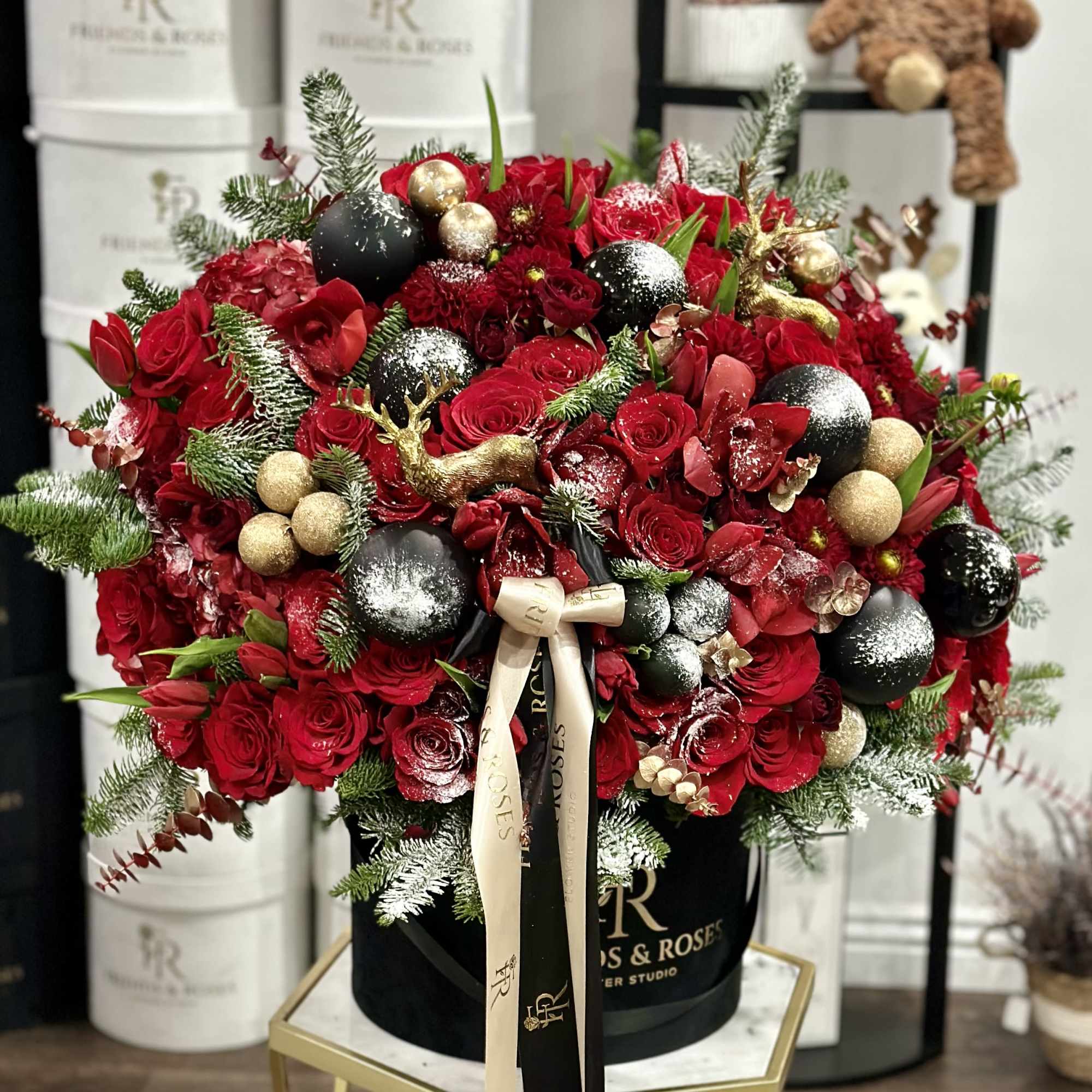 Red rose arrangement with gold and black ornaments in a black hat box