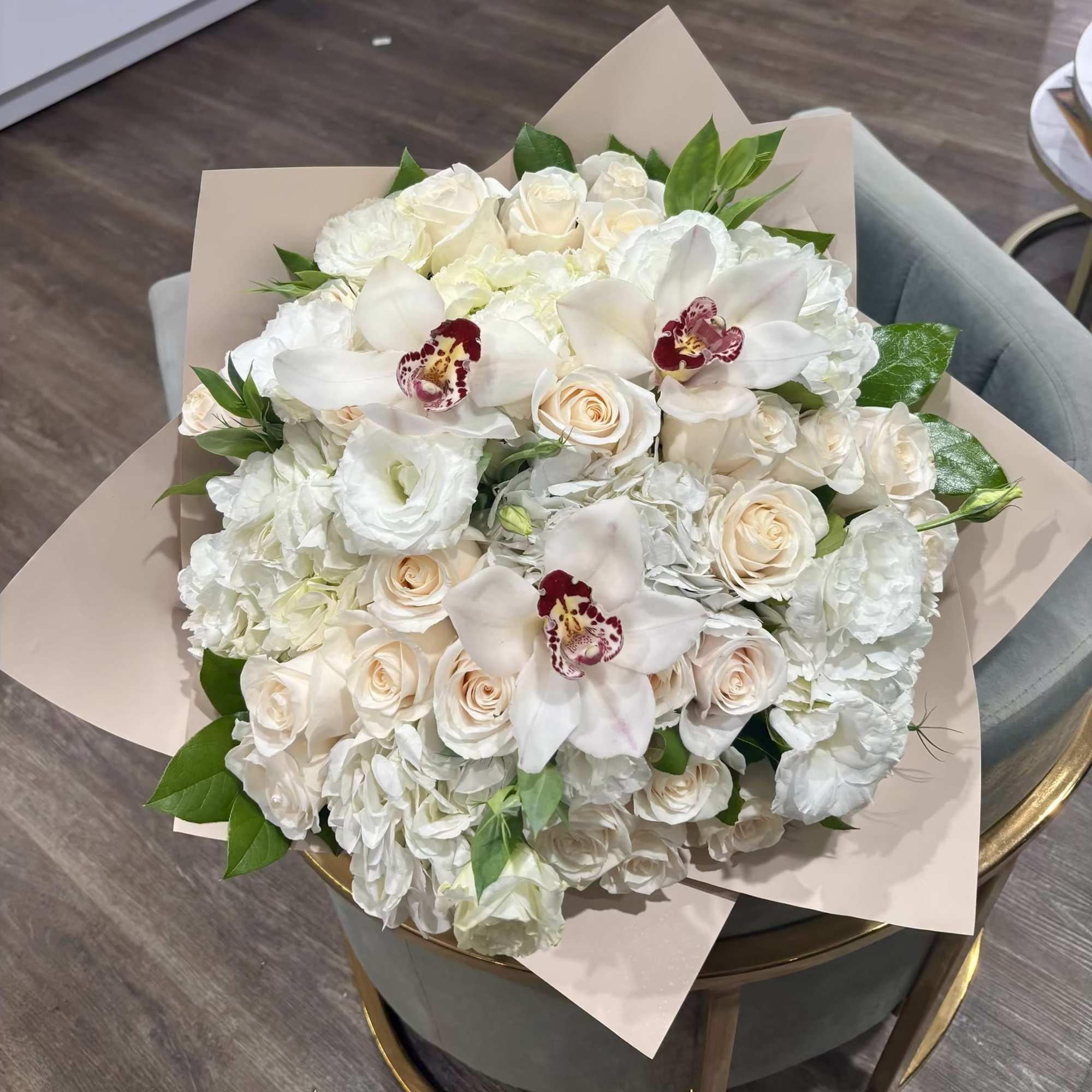White rose and orchid bouquet wrapped in pale paper