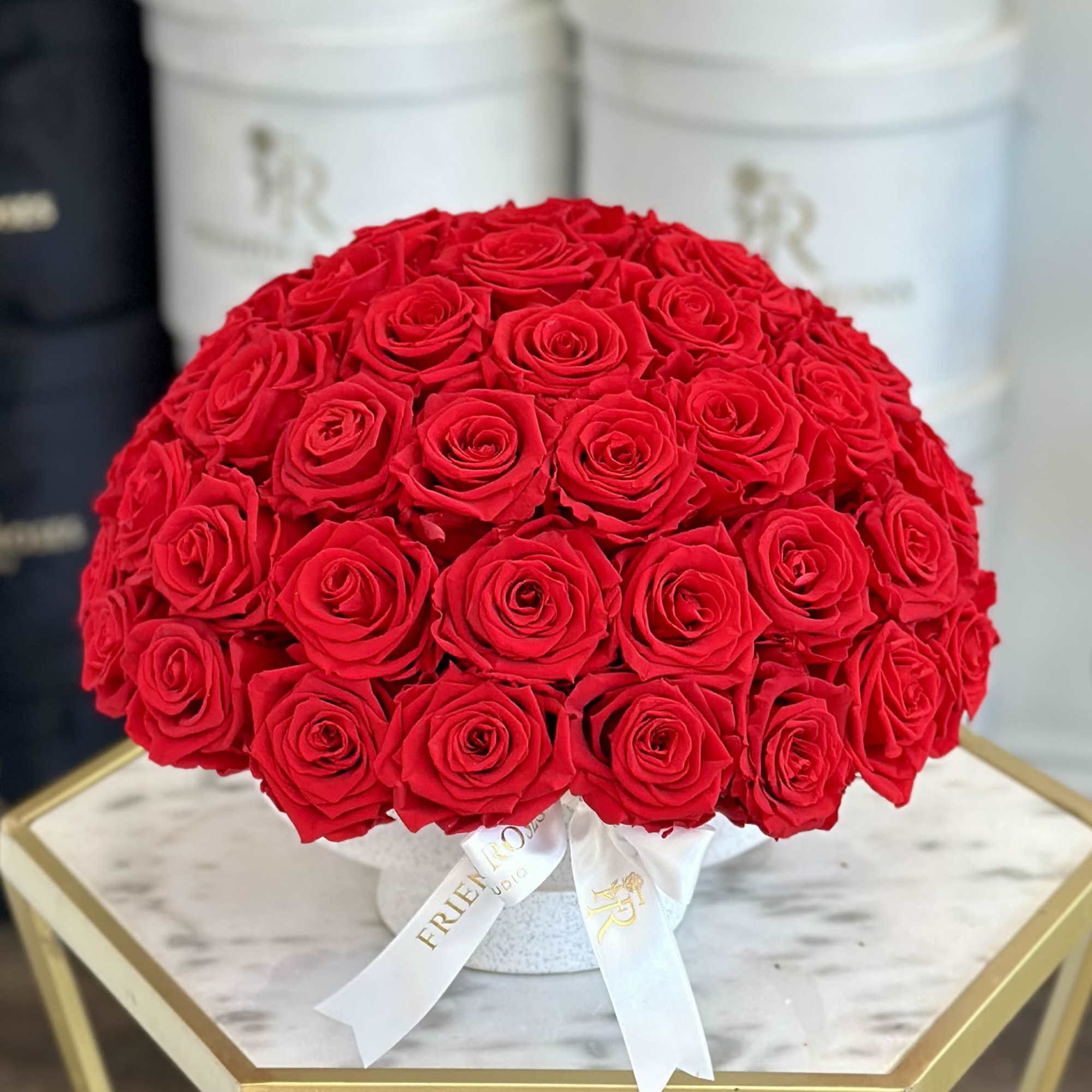 Round bouquet of red roses in a white hat box with a ribbon
