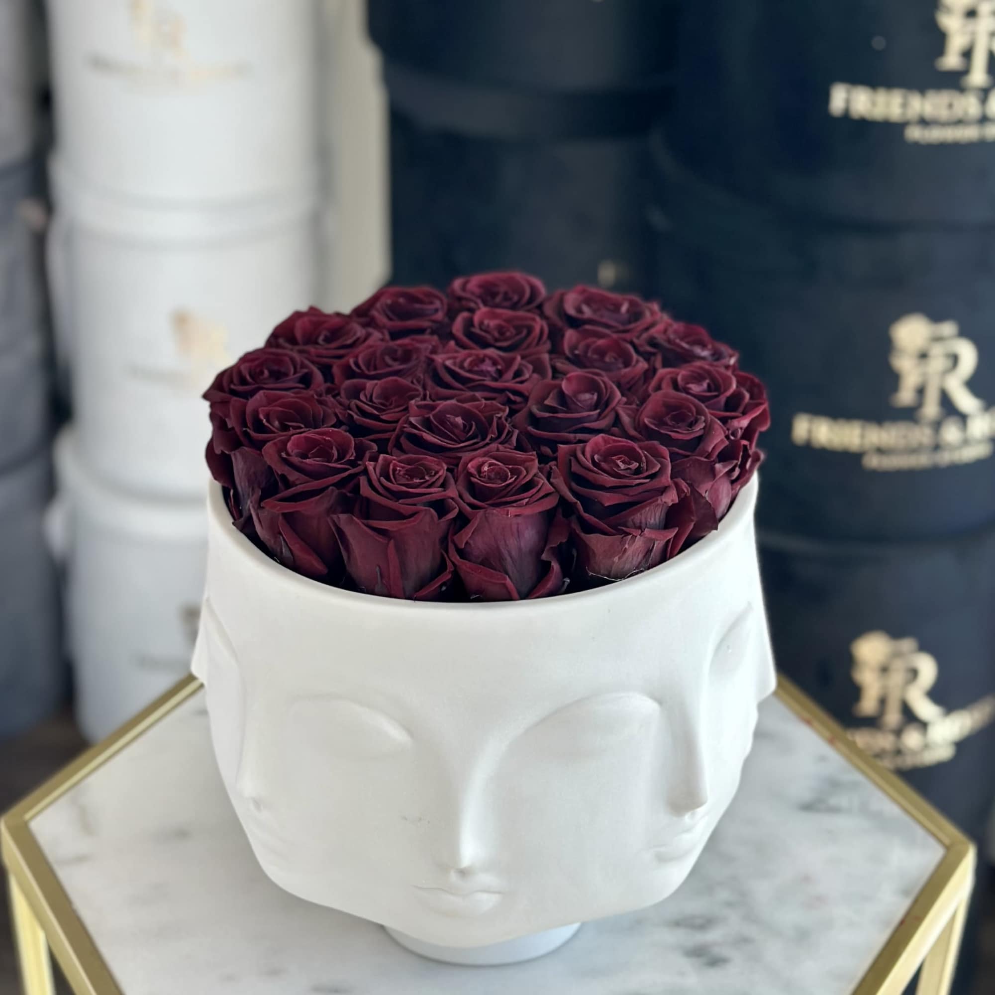 Deep burgundy roses arranged in a white sculpted face vase