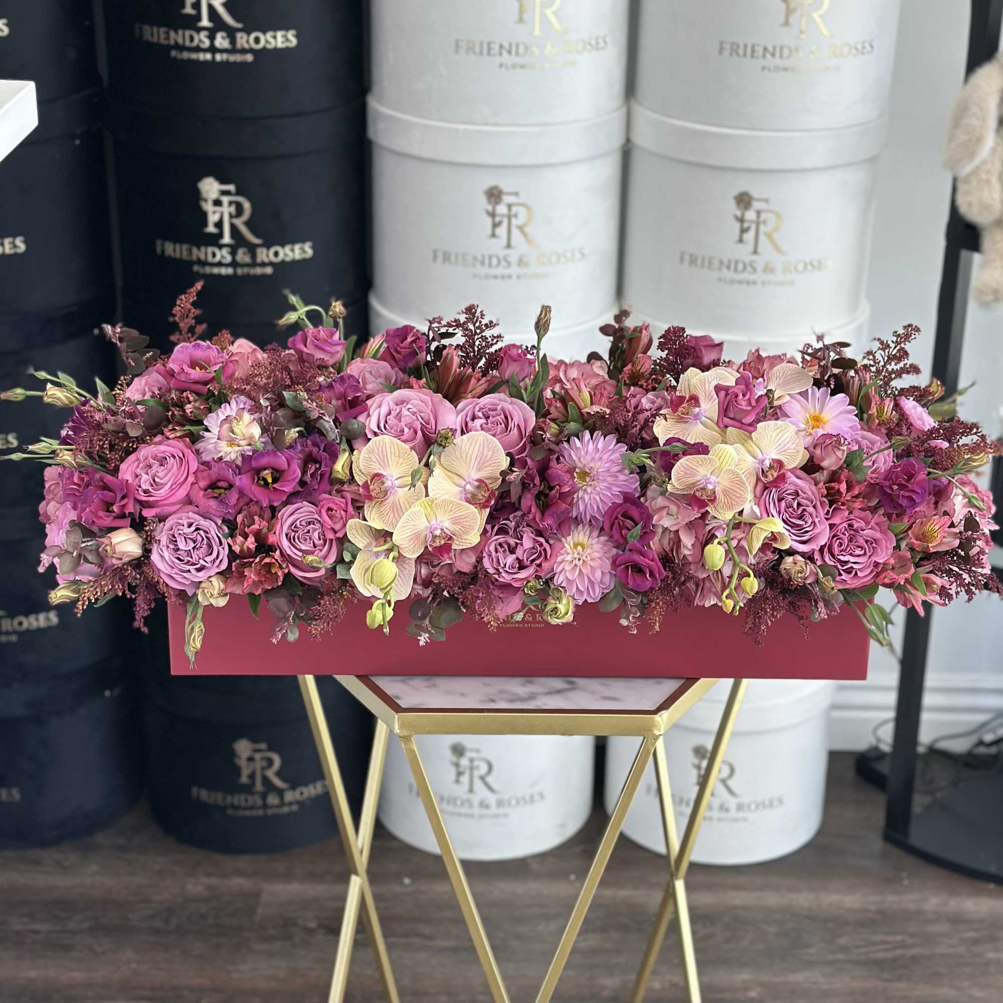 Long pink floral arrangement in a rectangular box on a gold stand