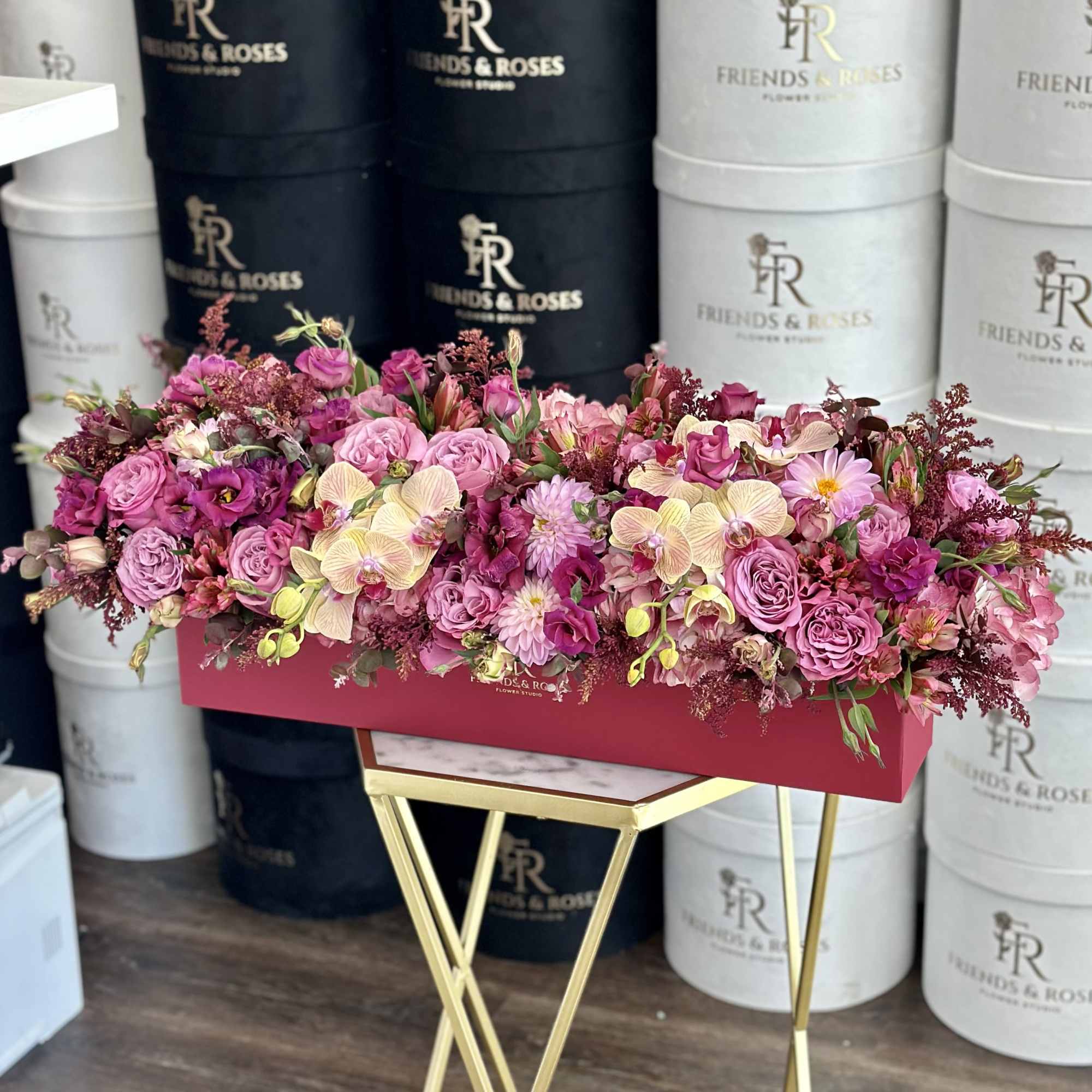 Pink floral arrangement in a rectangular box on a gold stand