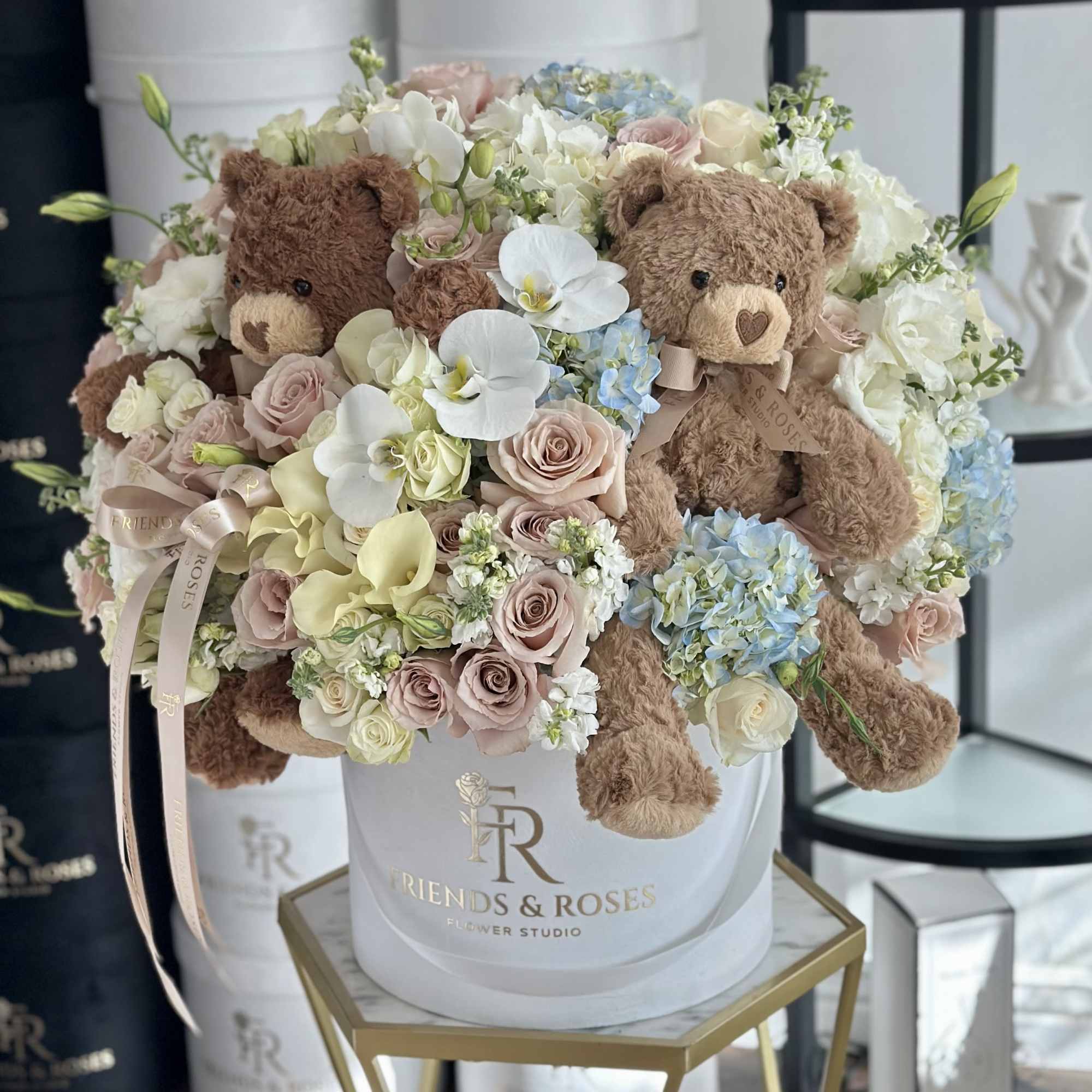 Bouquet of pastel roses, hydrangeas, and teddy bears in a white hatbox