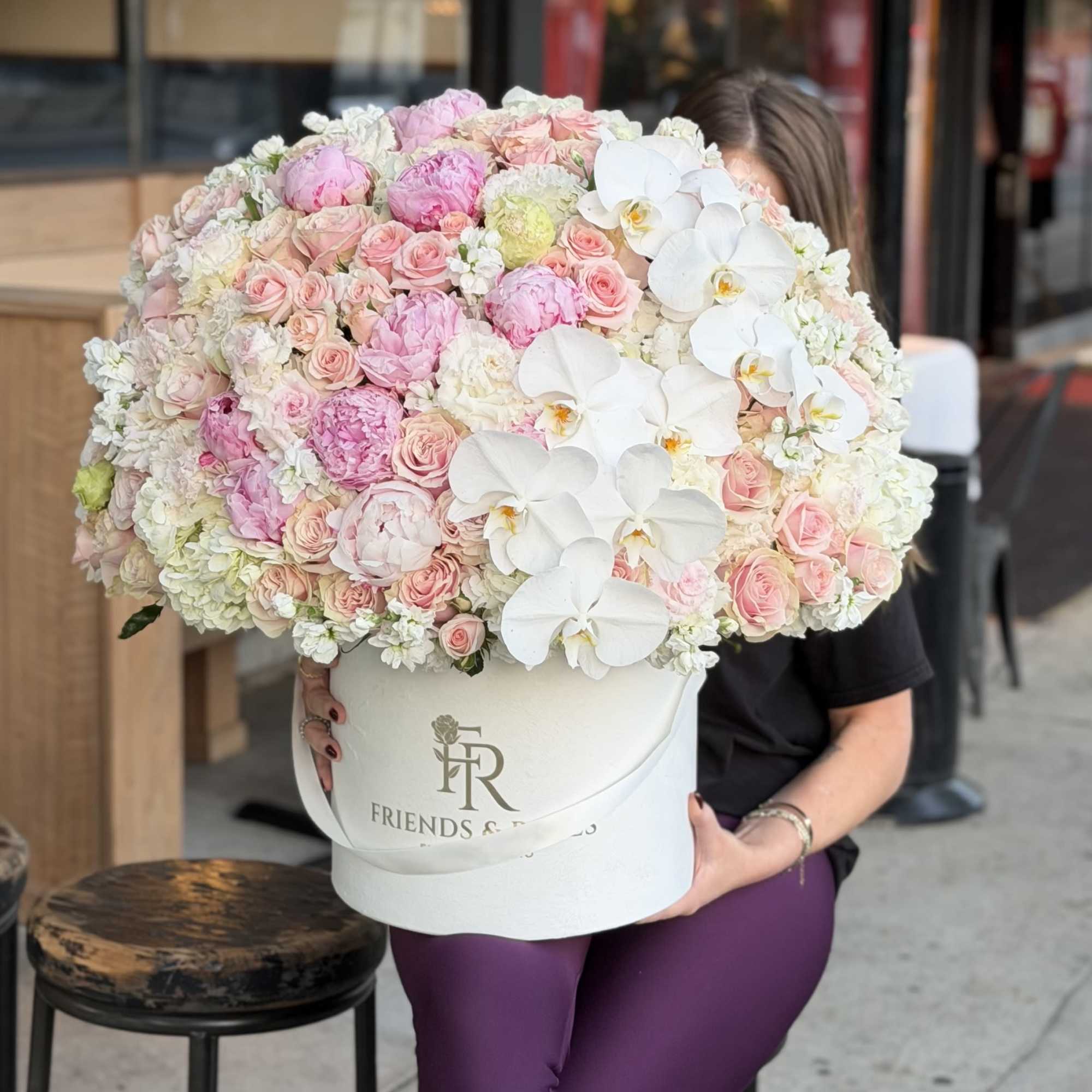 Large hatbox arrangement of pink roses, peonies, and white orchids