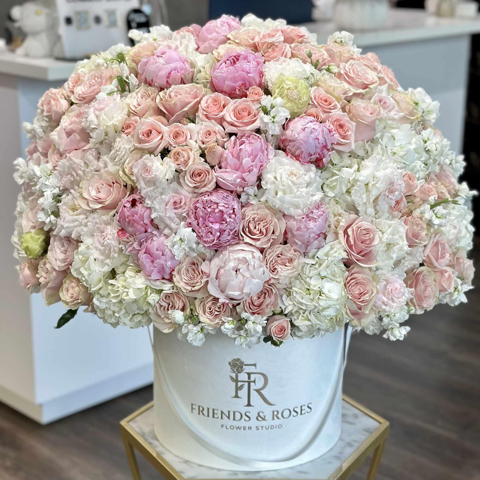 Large pastel bouquet of pink and white roses in a white hatbox