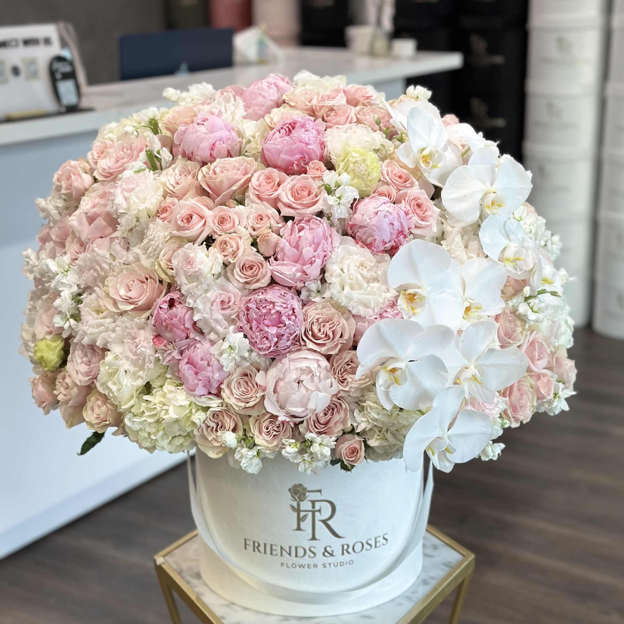 Large pastel bouquet of roses and white orchids in a white hatbox