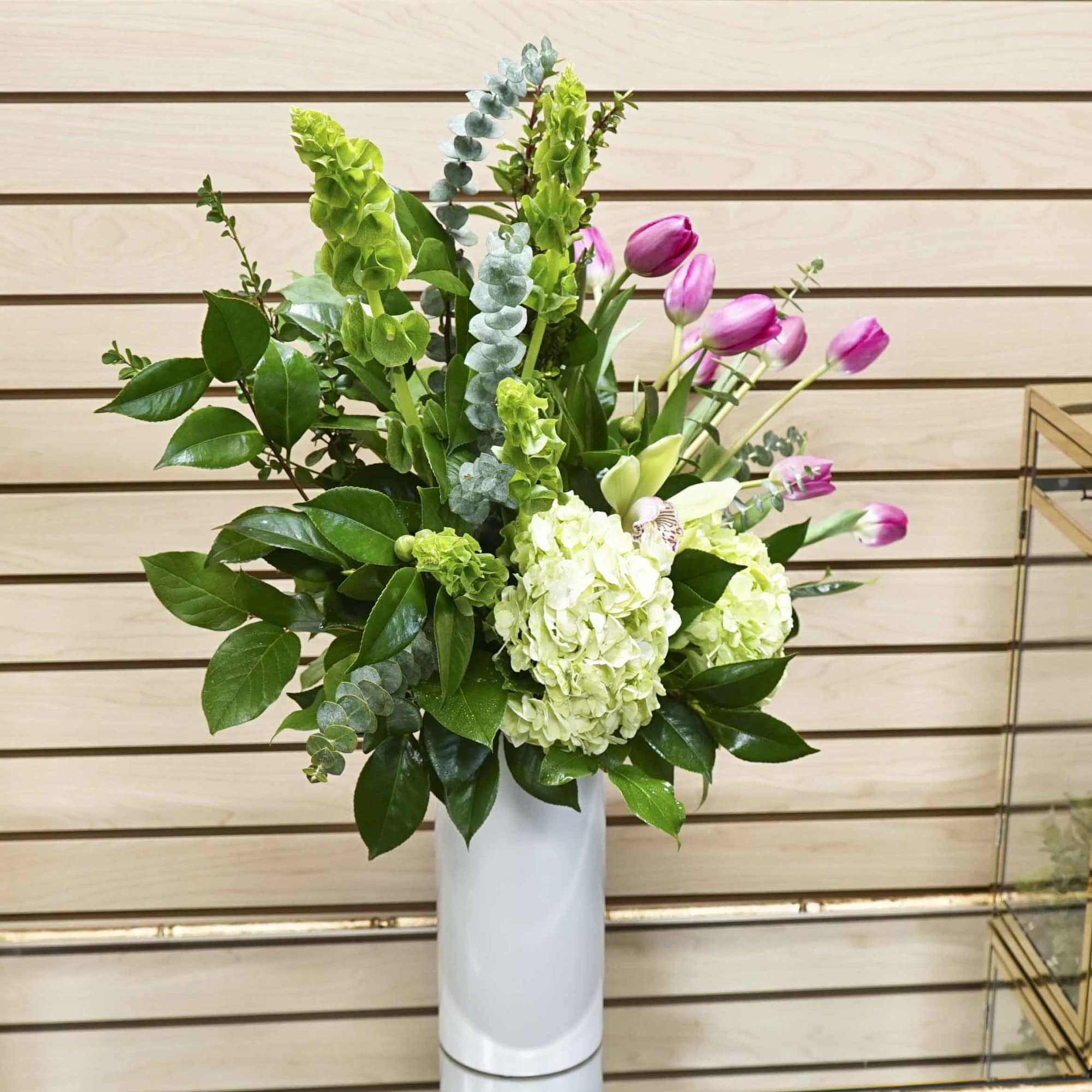 Pink tulips and white hydrangeas in a tall white vase