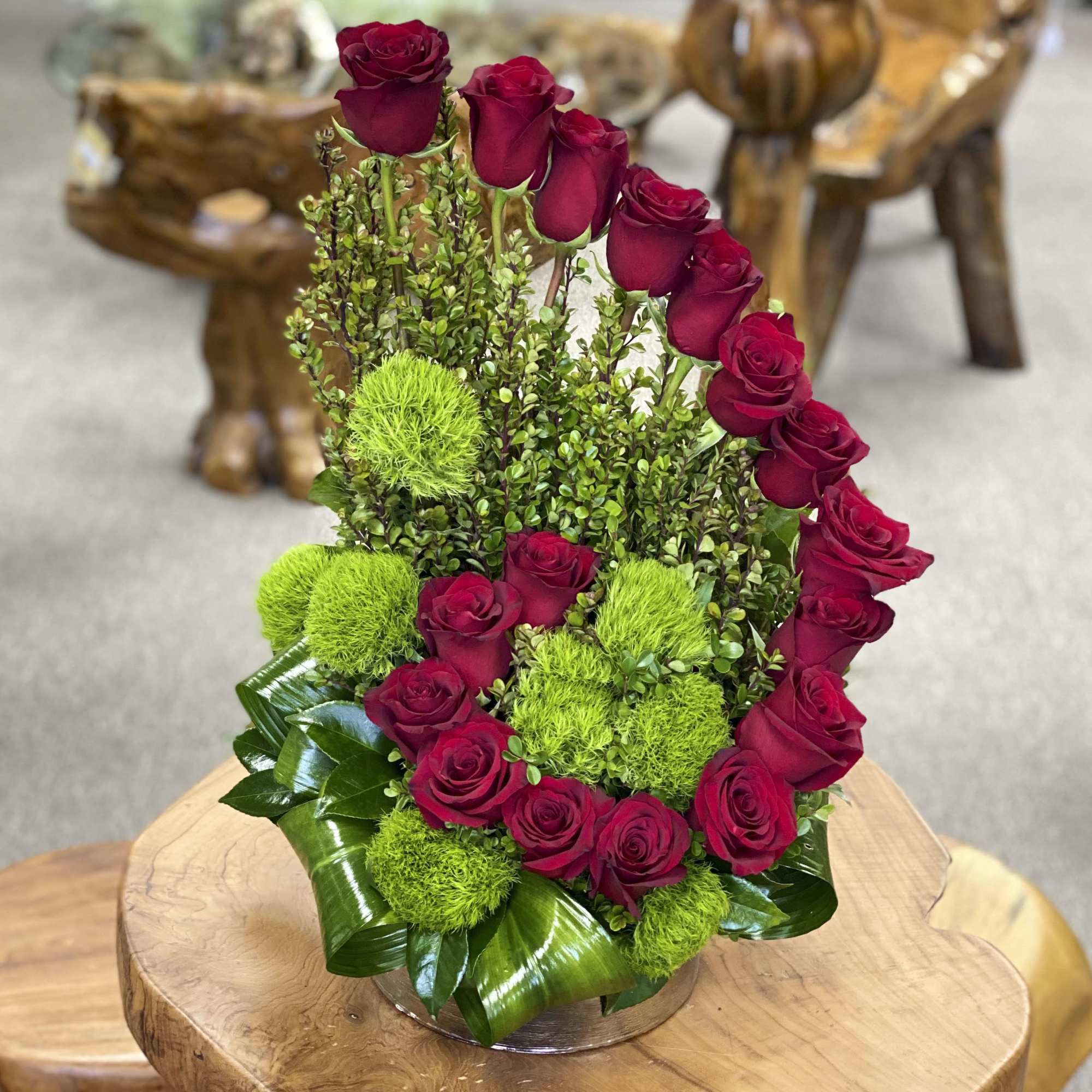 Red roses arranged with bright green pom-pom flowers in a low container