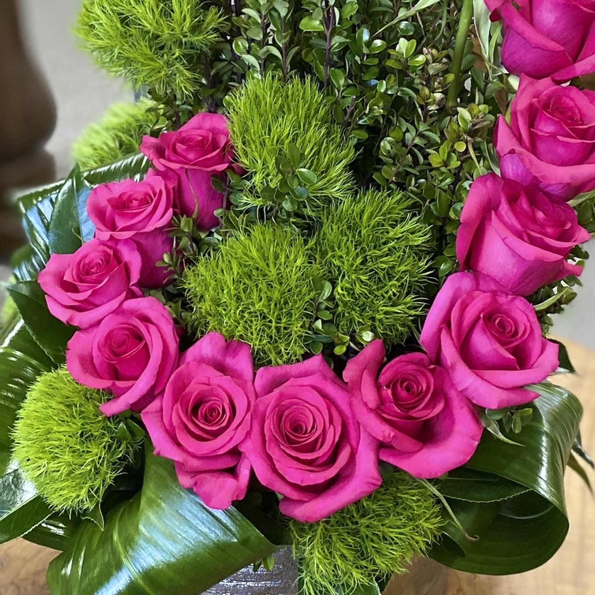 Bouquet of hot pink roses with bright green filler and glossy leaves