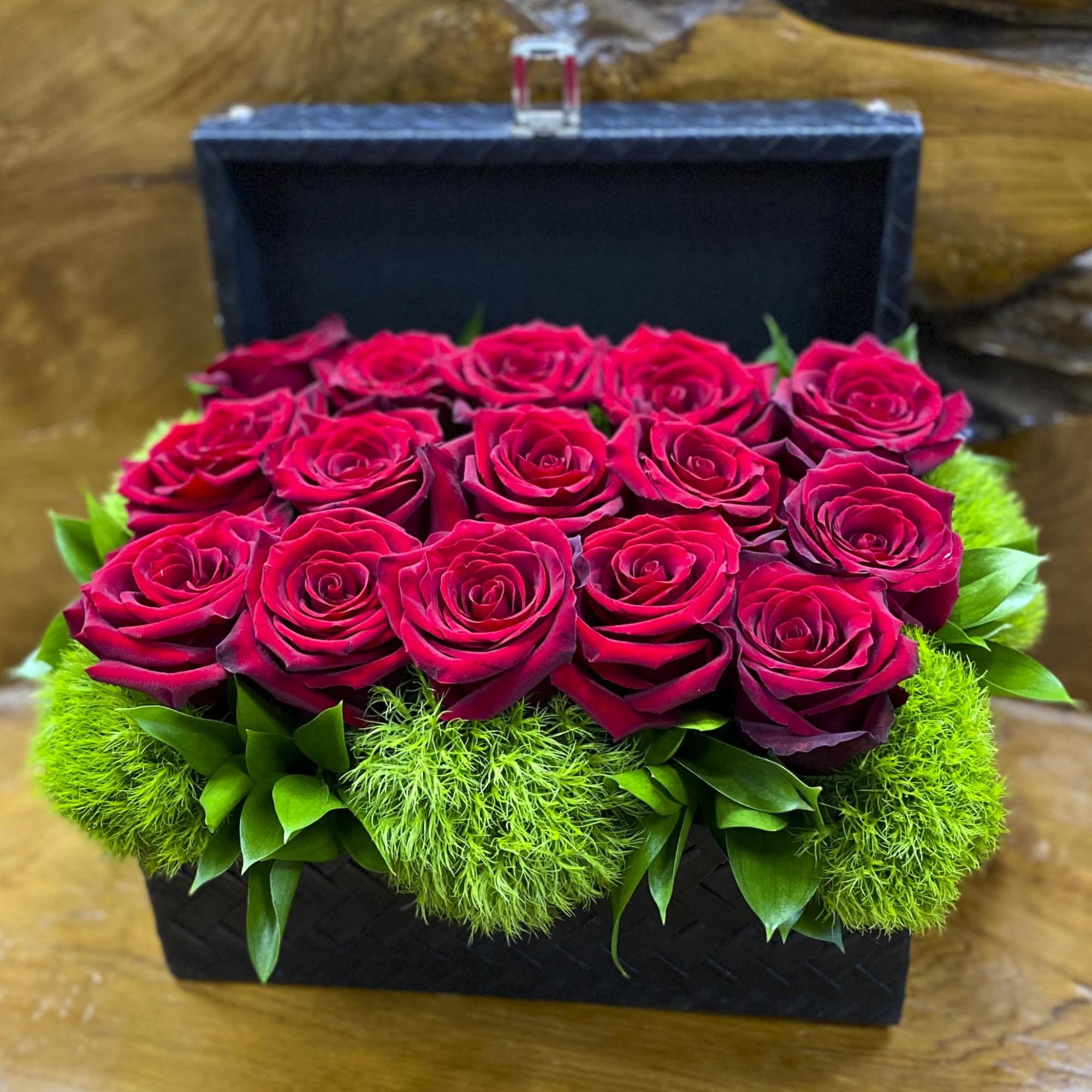 Box arrangement of red roses with bright green moss accents