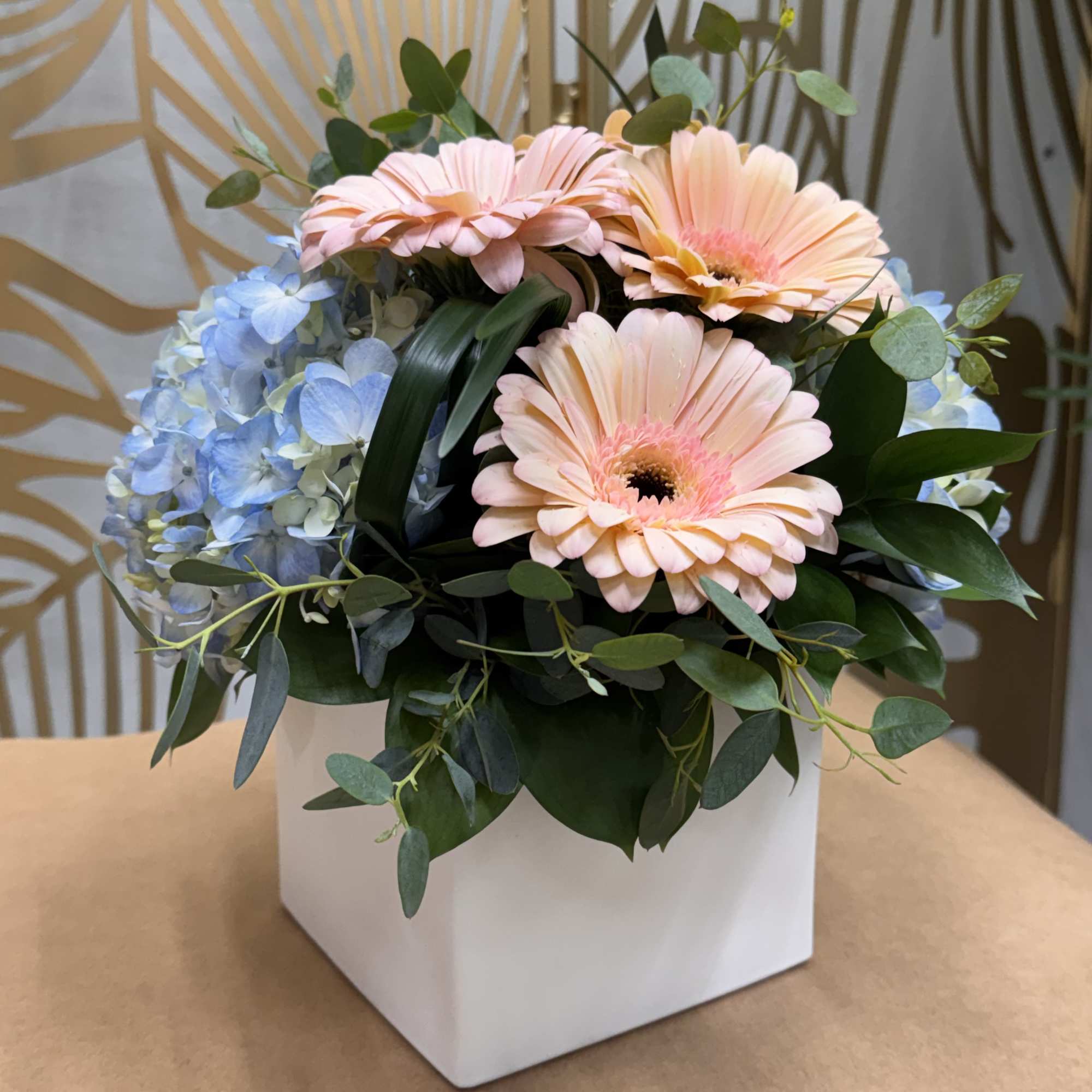 Peach gerbera daisies and blue hydrangeas in a white box