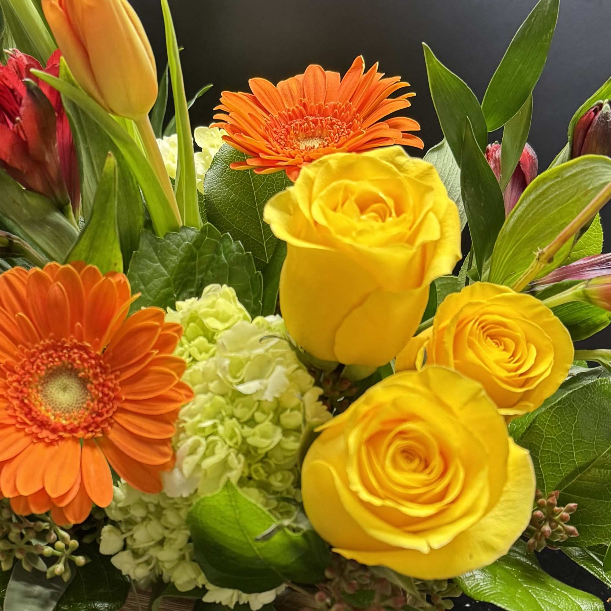 Yellow roses and orange gerbera daisies in a wooden box