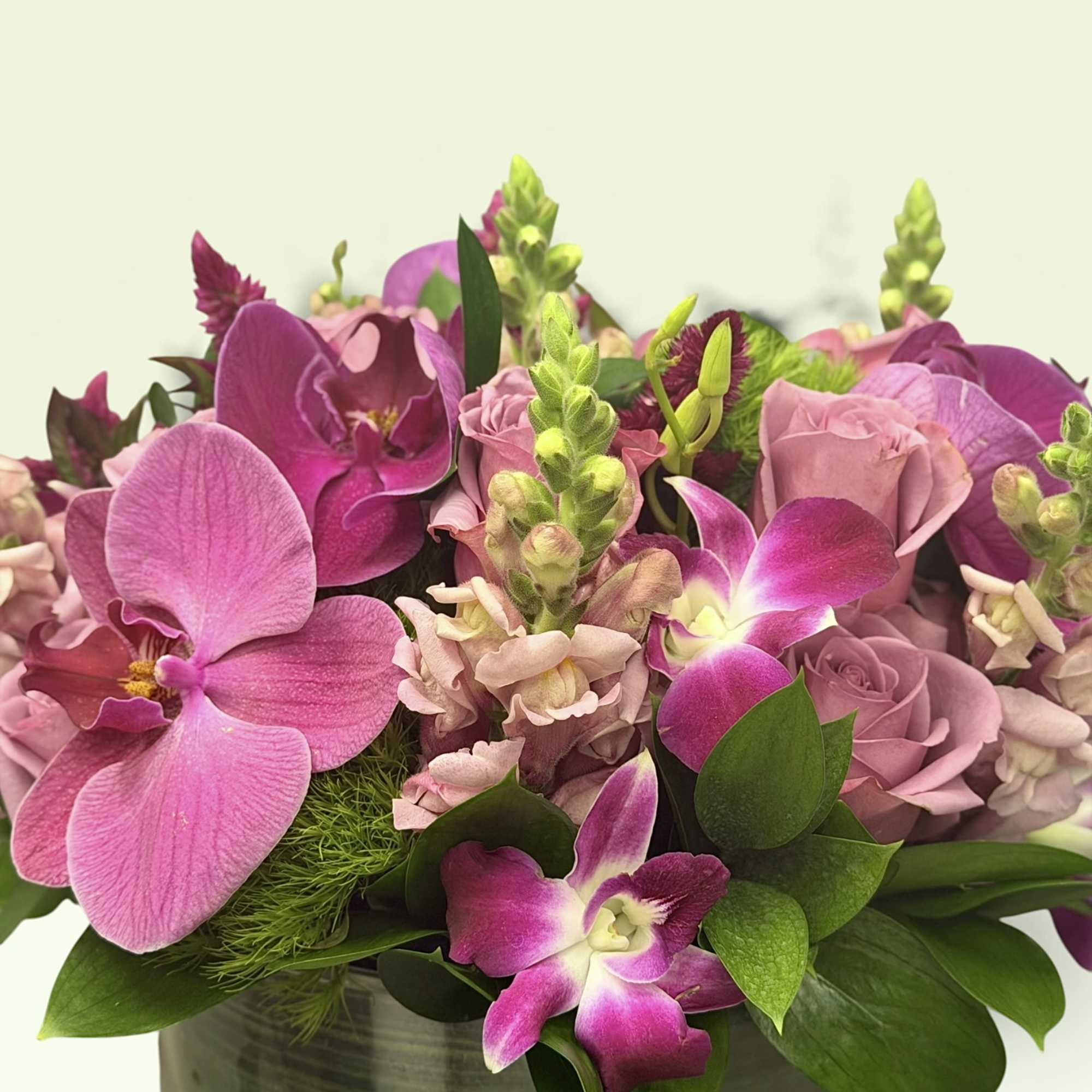 Pink orchids and roses arranged in a green ceramic vase