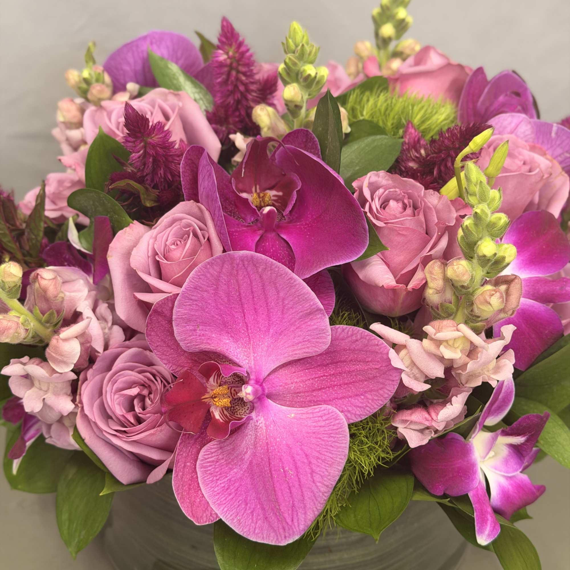 Pink roses and orchids arranged in a glass bowl vase
