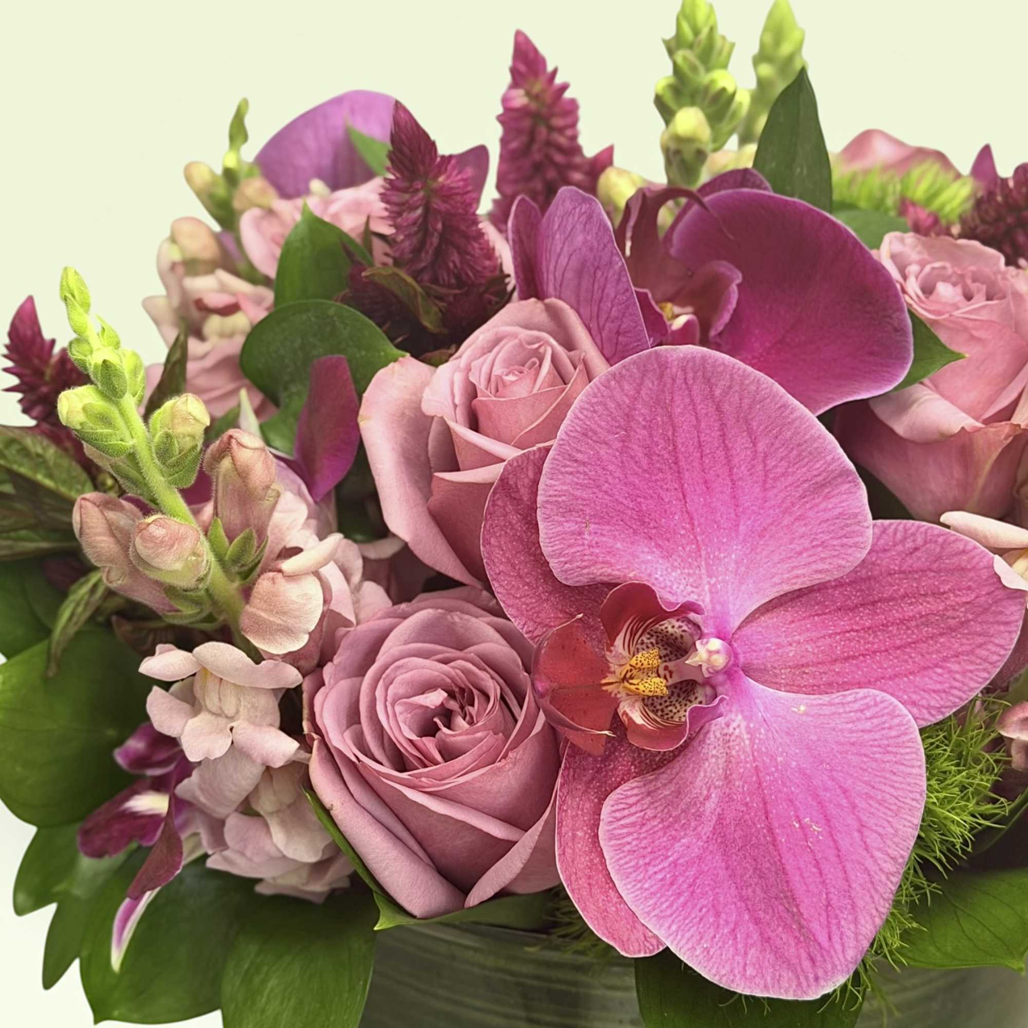 Pink roses and orchids arranged in a dark green vase