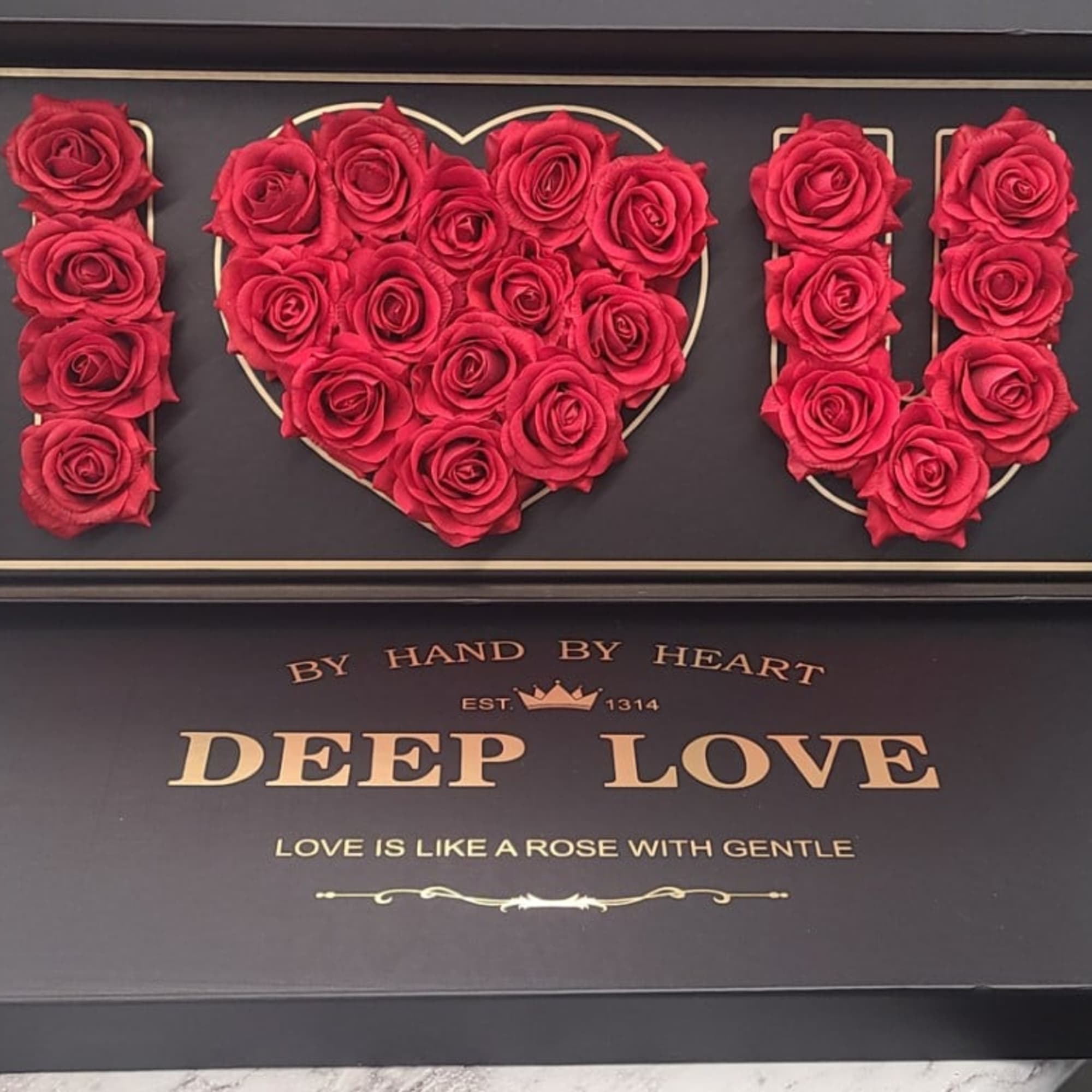 Red roses arranged to spell I heart U in a black display box