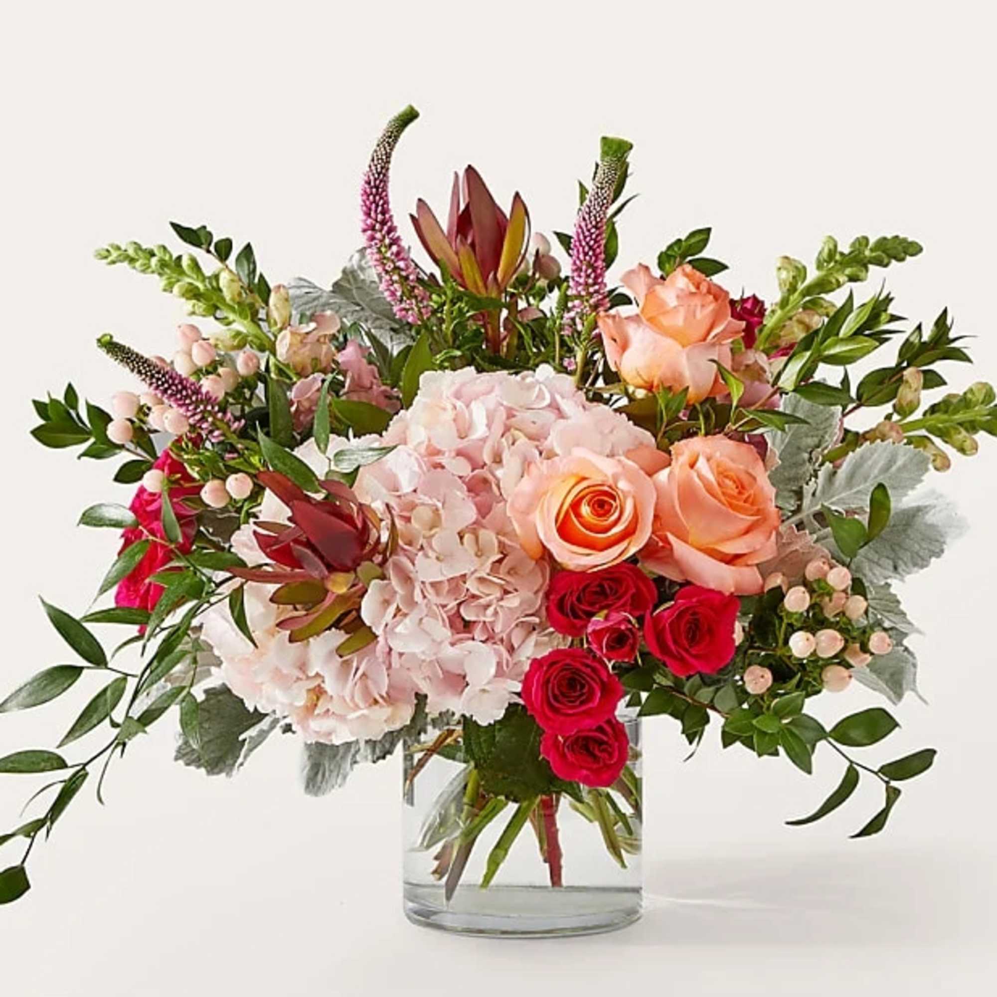Mixed bouquet of pink and peach flowers in a clear glass vase