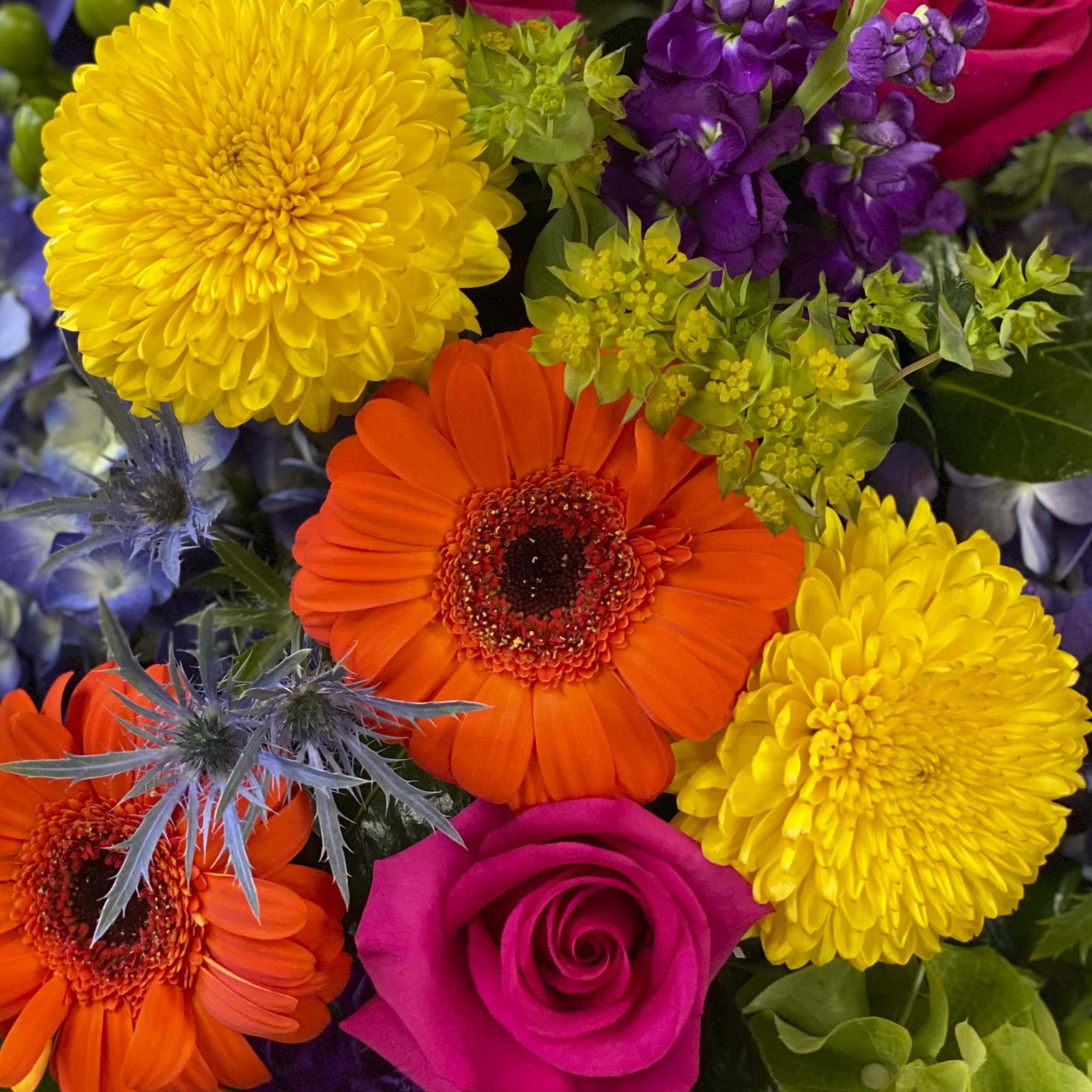 Close-up bouquet of yellow and orange flowers with a pink rose